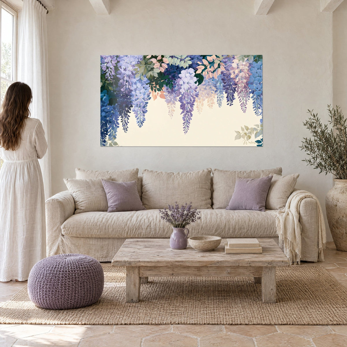 Schilderij hangende blauwe regen in lavendel- en blauwe trossen op ivoren achtergrond, vrouw in witte jurk van achteren, boven een bank in een lichte woonkamer