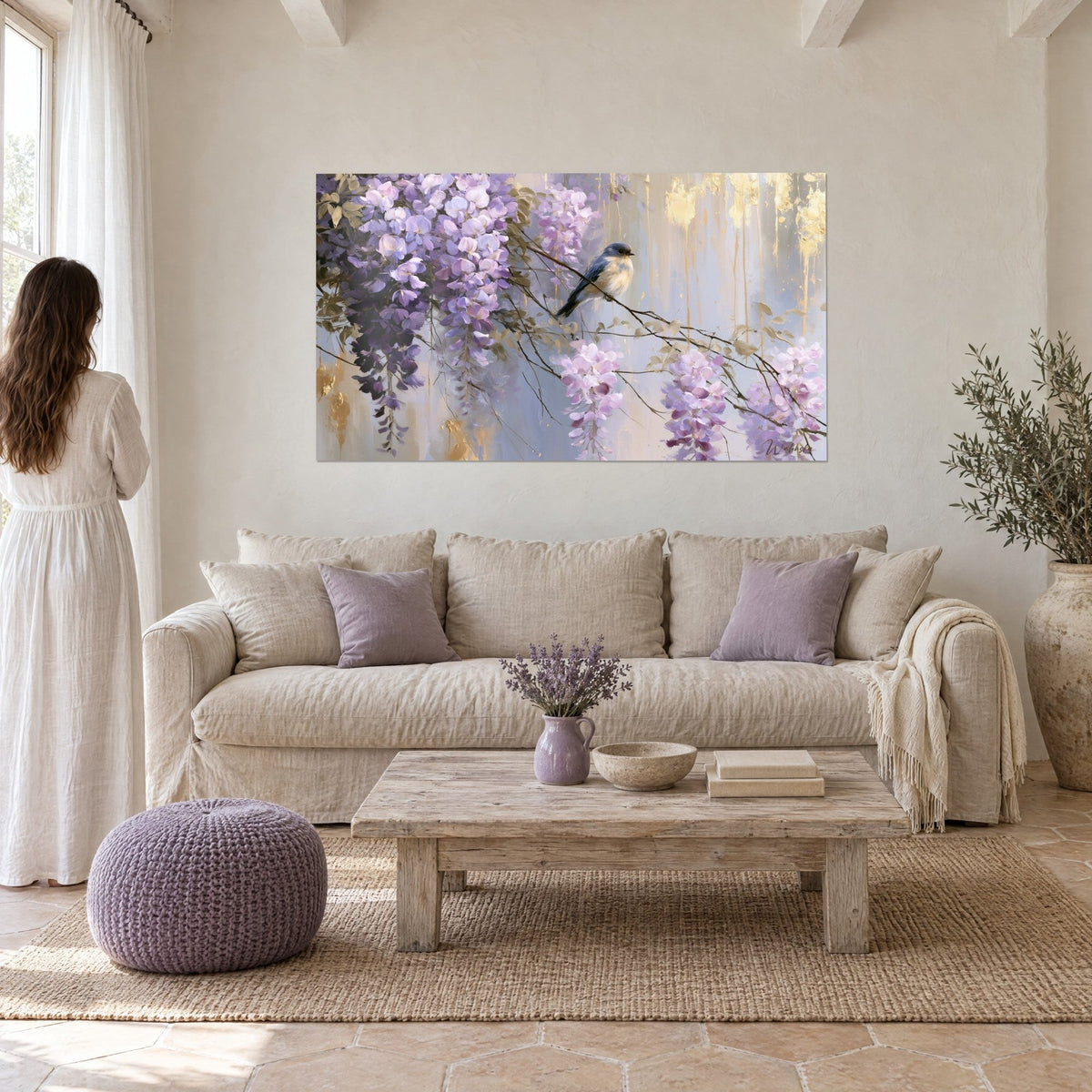 Tableau grappes de glycine mauves et oiseau bleu perché sur une branche fine, coulures dorées, au-dessus d'un canapé dans un salon lumineux