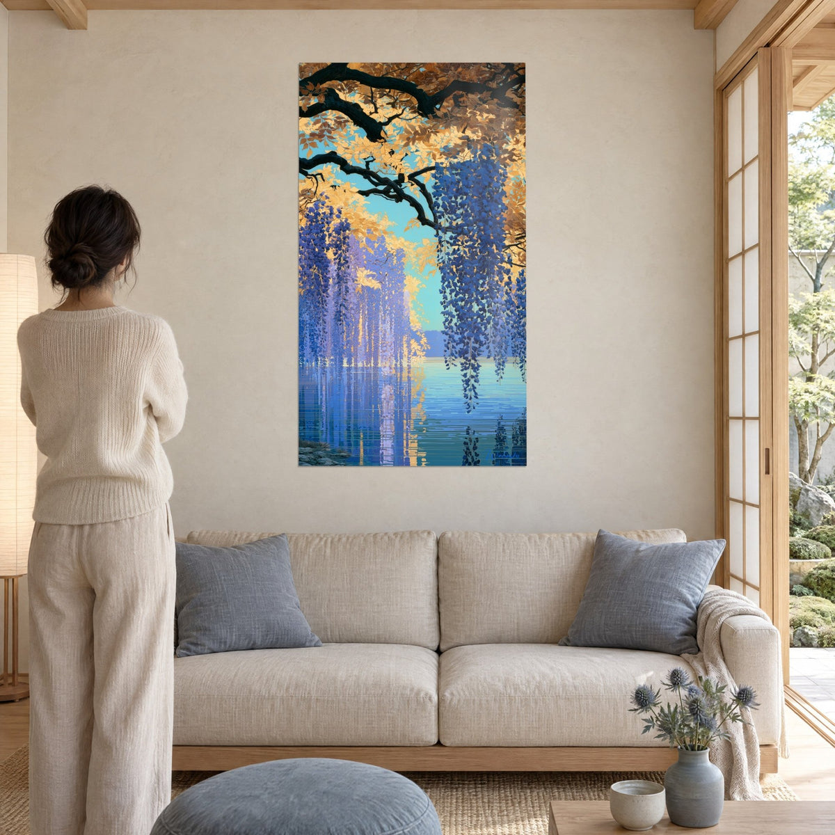 Schilderij met druiventrossen blauwe glycine in marineblauw onder een gouden tak, weerspiegelingen op een turquoise meer, vrouw van achteren, boven een bank in een lichte woonkamer