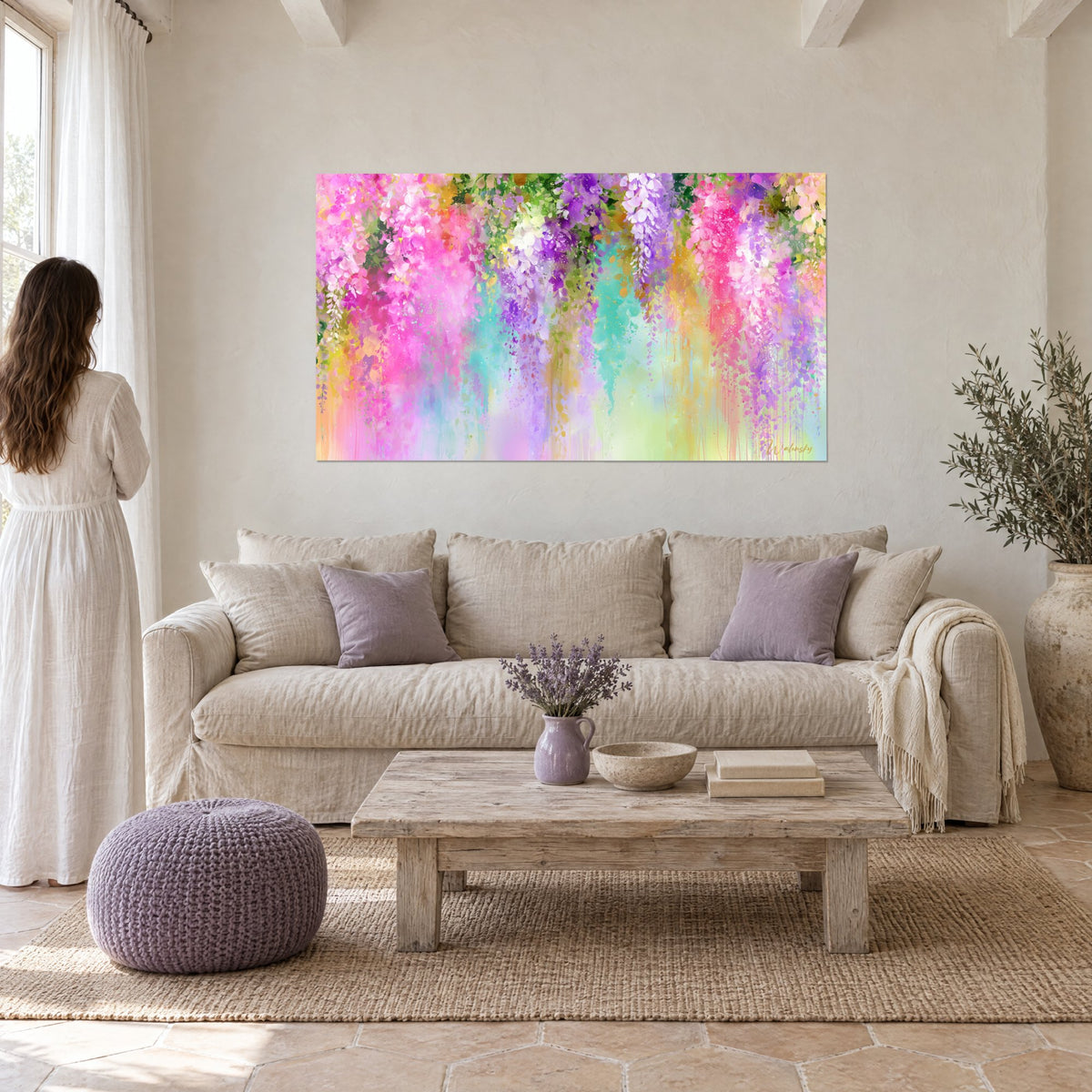 Cuadro de glicinias fucsia y lila en cascada, goteos turquesa, mujer de espaldas, sobre un sofá en un salón luminoso