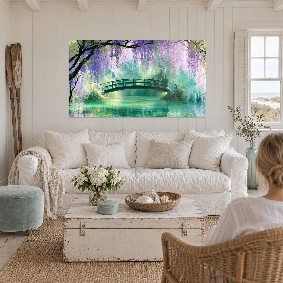 Wall art green arched footbridge under mauve and pink wisteria, turquoise pond, woman seen from behind, above a sofa in a bright living room