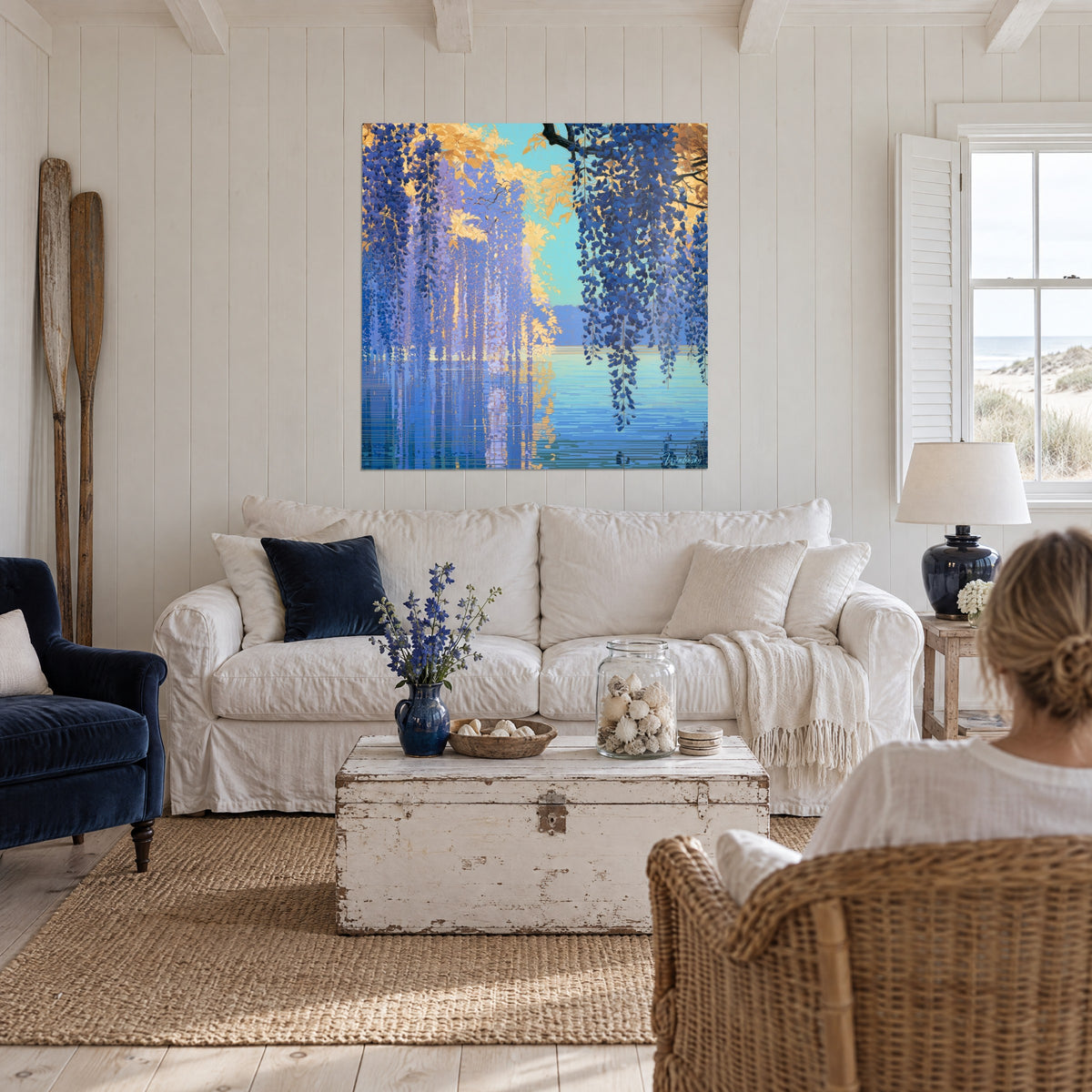 Schilderij blauweregen in marineblauwe trossen en gouden gebladerte boven een turquoise meer, boven een bank in een lichte woonkamer