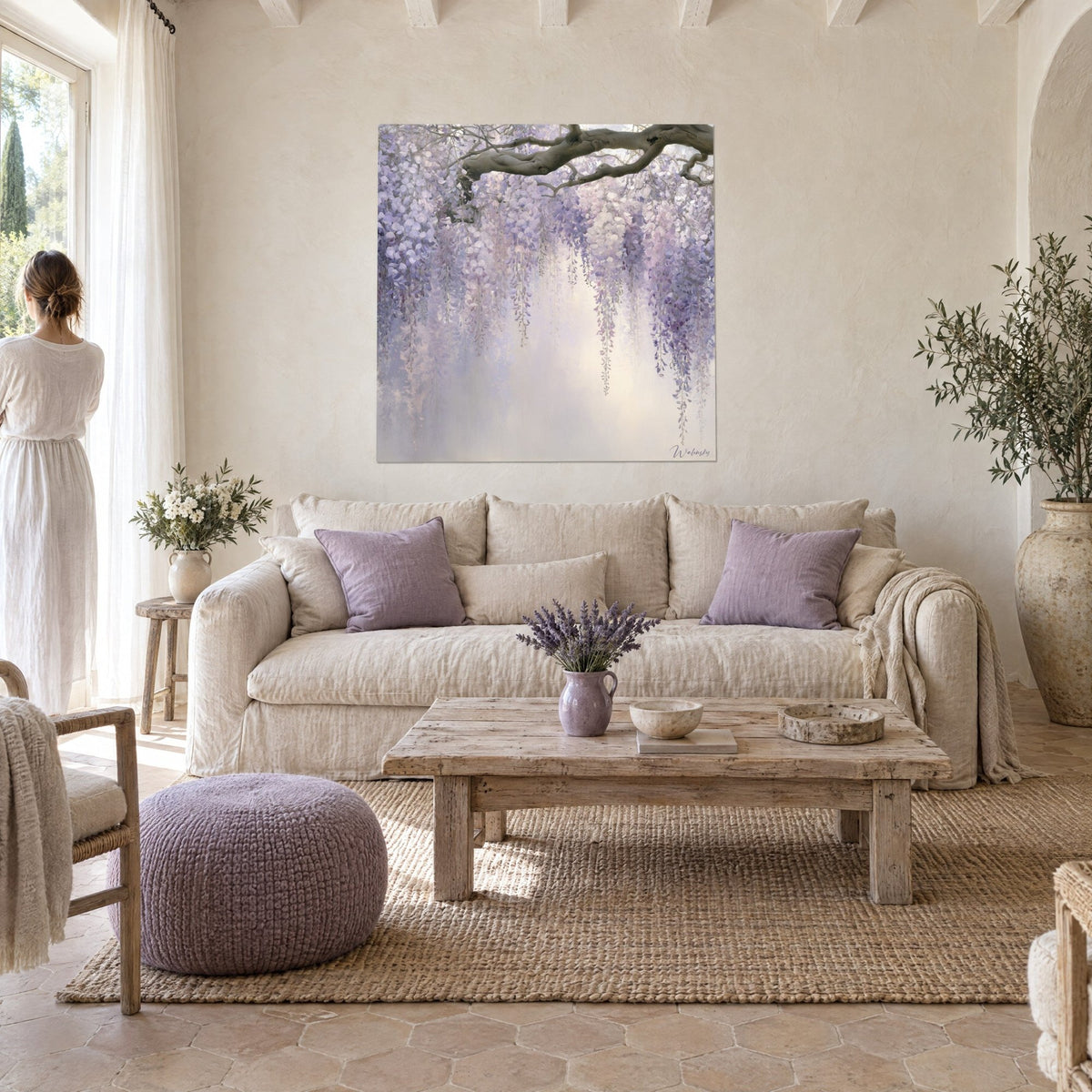 Wall art with cascading lilac wisteria clusters beneath a brown branch, mauve and ivory tones, above a sofa in a bright living room