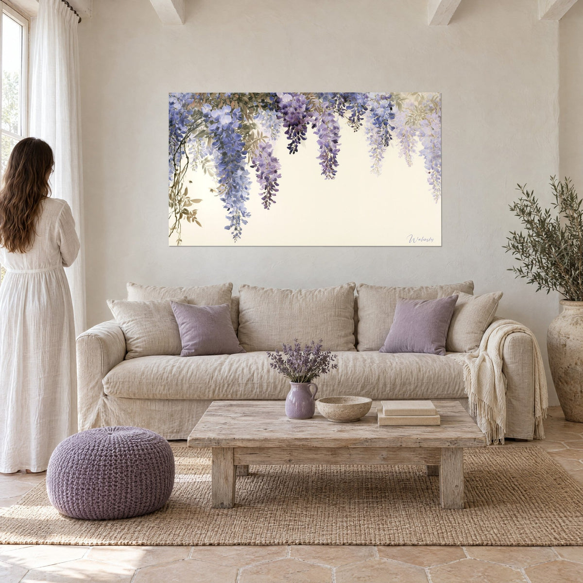 Wall art with drooping clusters of wisteria in lavender blue and mauve on an ivory background, a few discreet bees, above a sofa in a bright living room