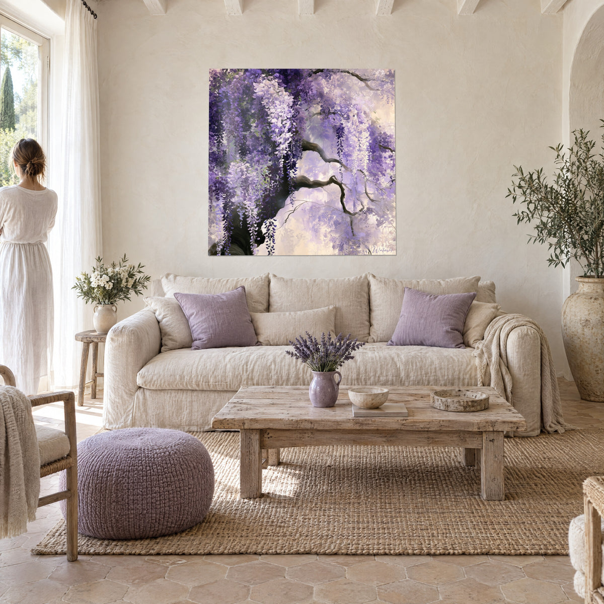 Schilderij wisteria in watervallen van paarse en ivoorkleurige trossen op een knoestige tak, een vrouw van achteren, boven een bank in een lichte woonkamer