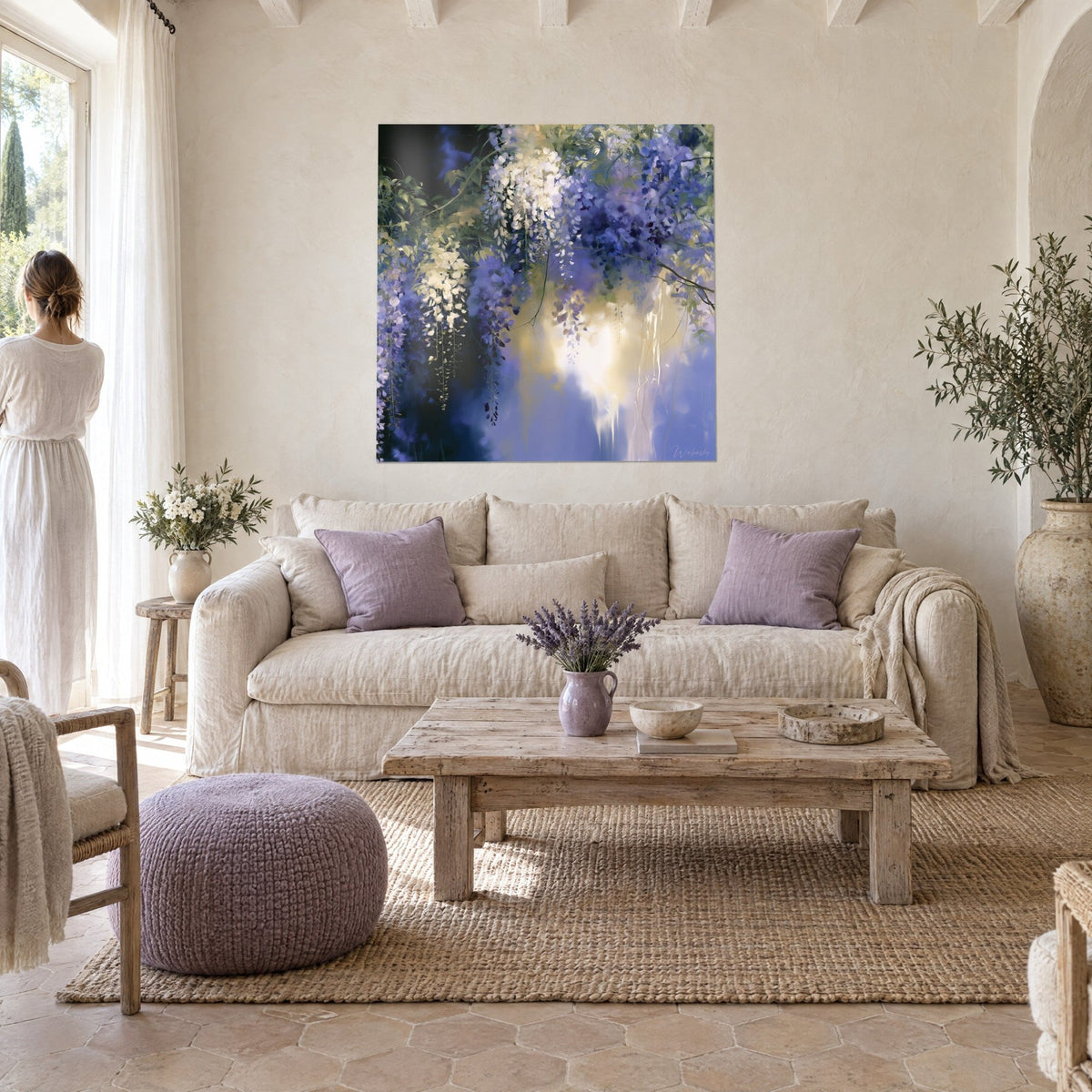 Quadro glicine a grappoli pendenti, malva e bianco crema, luce dorata al centro, donna di spalle, sopra un divano in un soggiorno luminoso