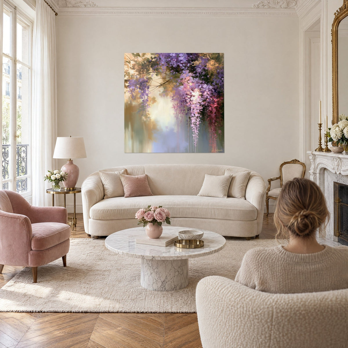 Wall art wisteria in clusters of mauve and pink on golden ochre background, a woman seen from behind above a sofa in a bright living room