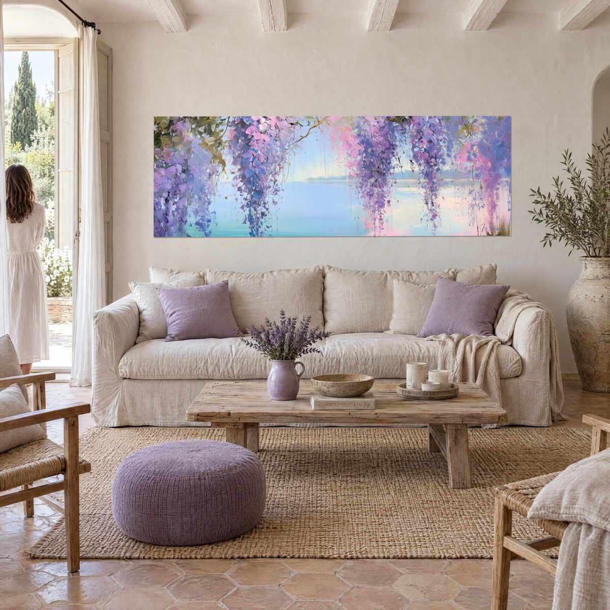 Gemälde mit mauven und rosa Blauregengrappen über einem ruhigen blauen See, eine Frau von hinten, über einem Sofa in einem hellen Wohnzimmer