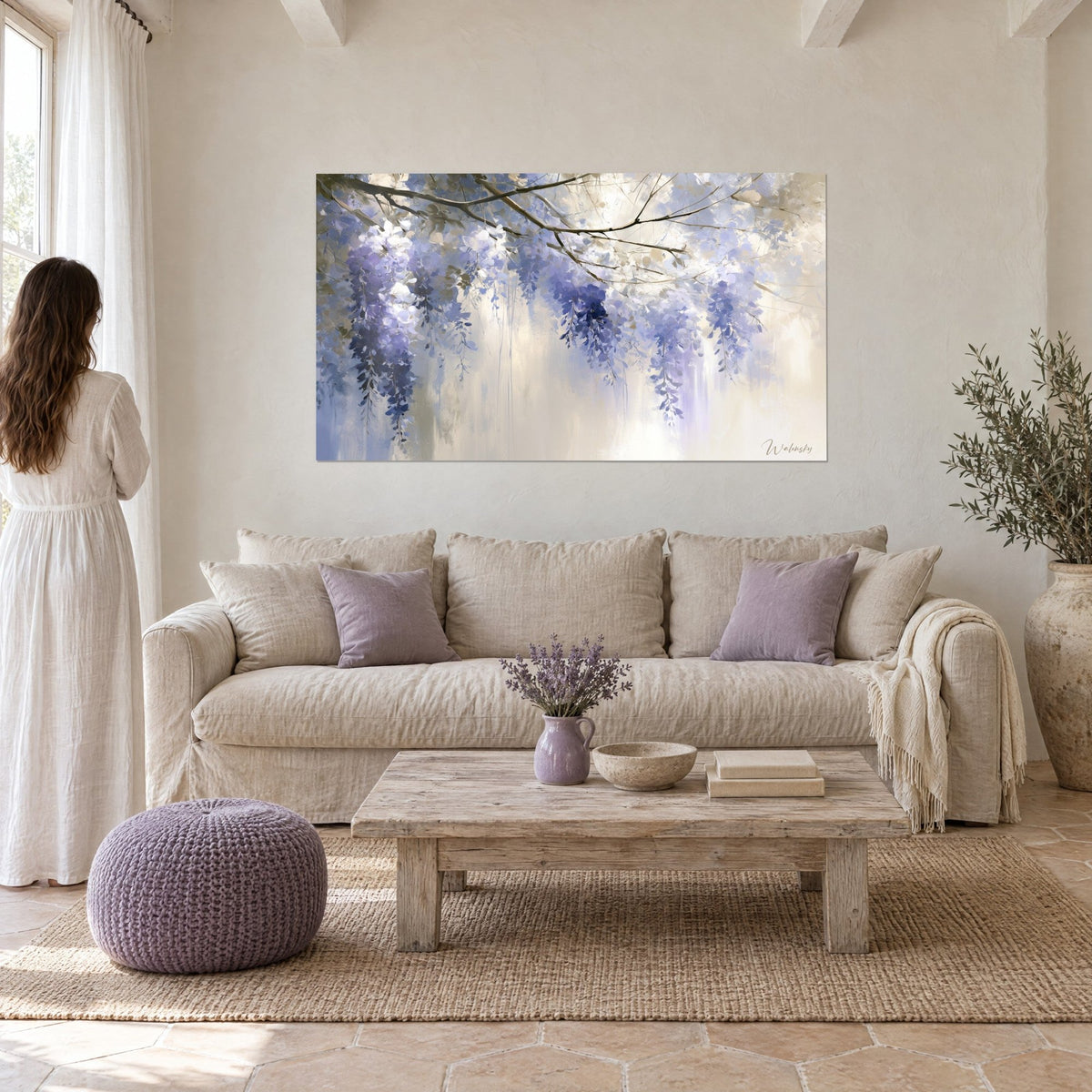 Wall art wisteria in lavender clusters on a fine branch, misty beige background, woman in a white dress, above a sofa in a bright living room