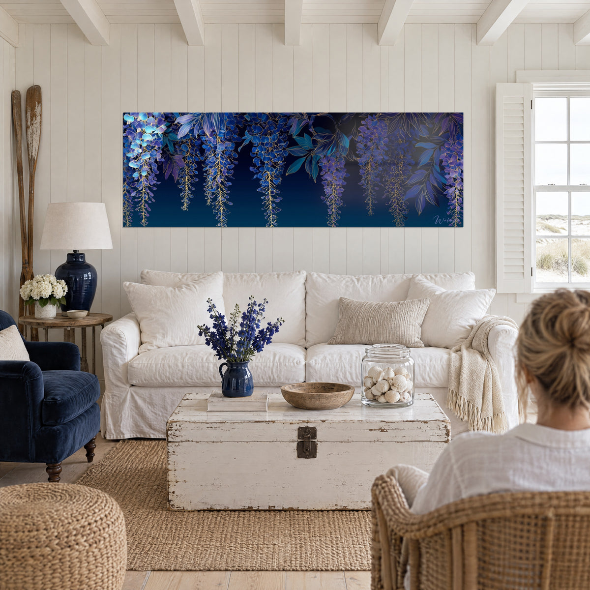 Schilderij trossen blauwe regen in nachtblauw en violet, omlijnd met goud, marineblauwe achtergrond, twee personen van achteren boven een bank in een lichte woonkamer