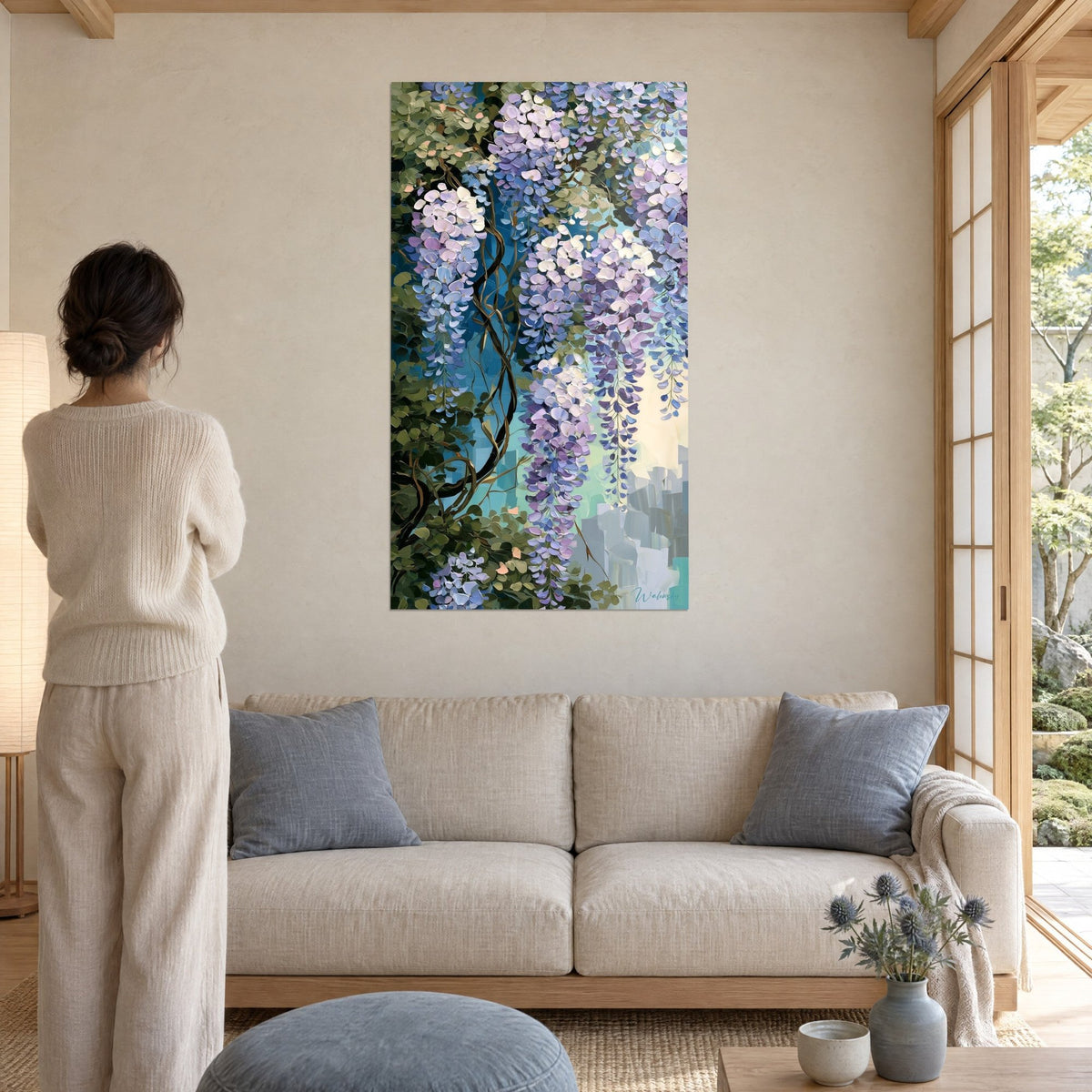 Wall art cascading wisteria, purple clusters and emerald green foliage, woman seen from behind, above a sofa in a bright living room