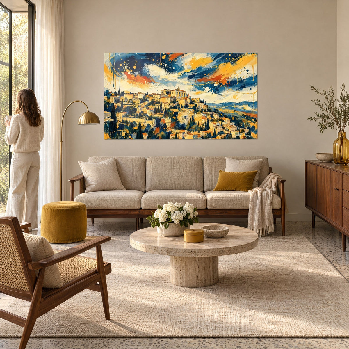 Wall art Gordes hilltop village in midnight blue and ochre, sky splashed with orange paint, a woman seen from behind, above a sofa in a bright living room