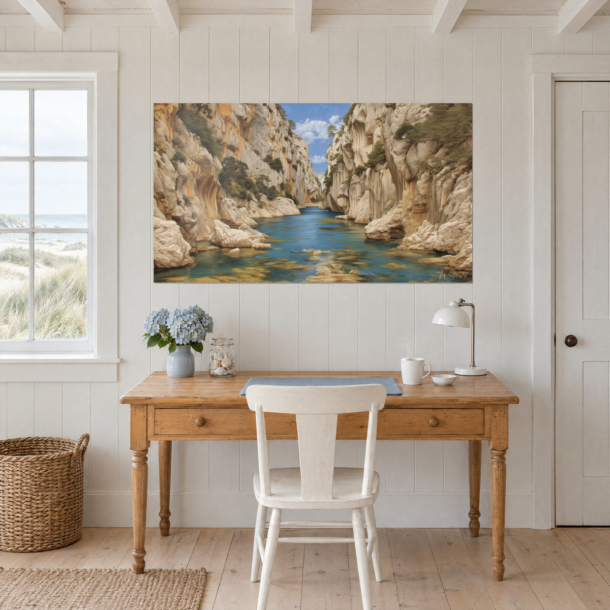 Wall art secluded cove between two cream stone walls, blue sky and cyan water, hung above a light wood desk