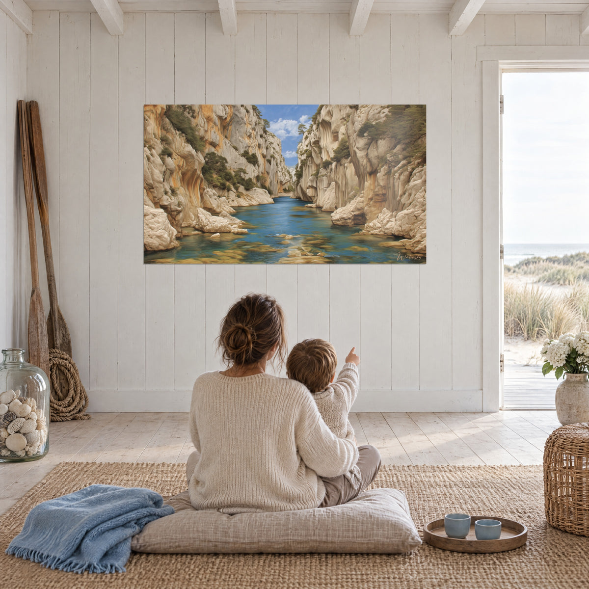 Wall art fjord of golden limestone and azure water, sculpted cliffs, mother and child seen from behind sitting on a cushion facing the white wall
