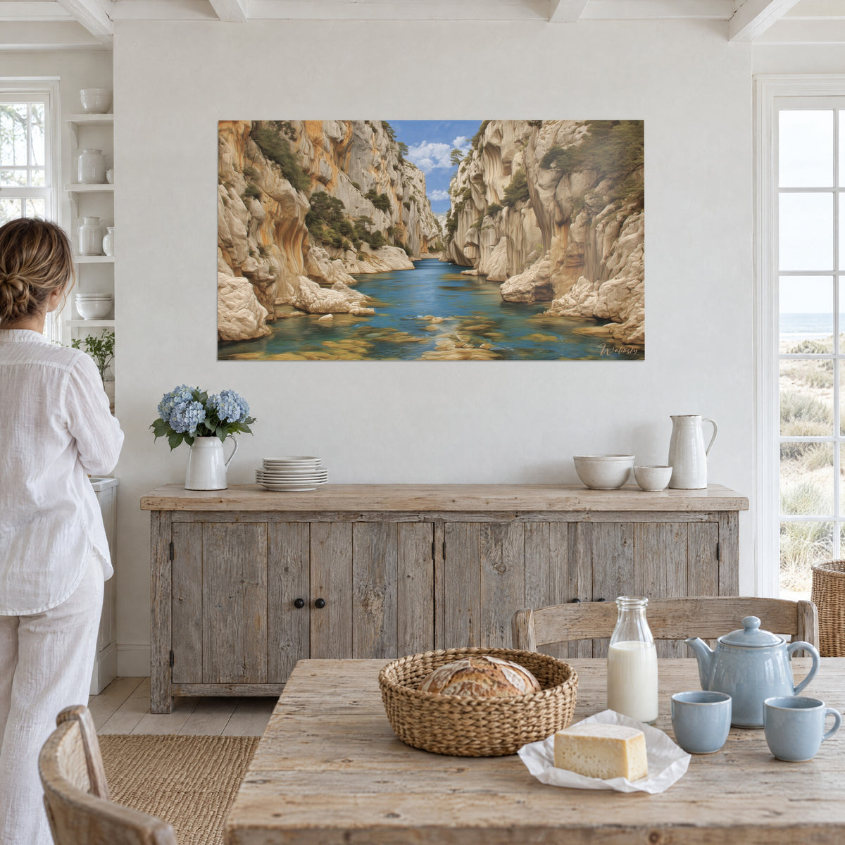 Wall art wild gorge with eroded white rocks, turquoise reflections and green pines, hung in a coastal-style living room, person seen from behind