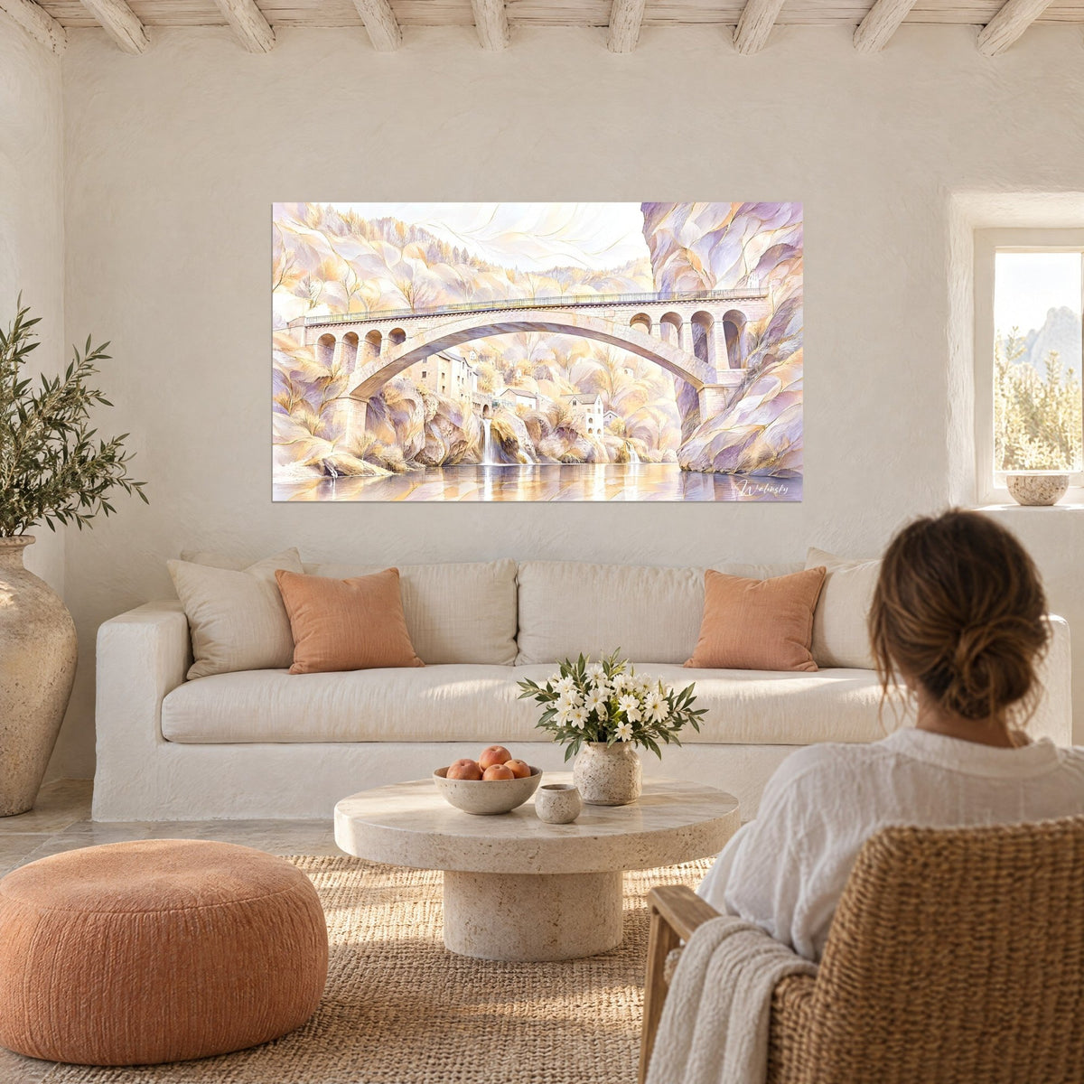 Tableau pont de pierre en arc doré et mauve sur rivière, regardé de dos, au-dessus d'un canapé dans un salon lumineux