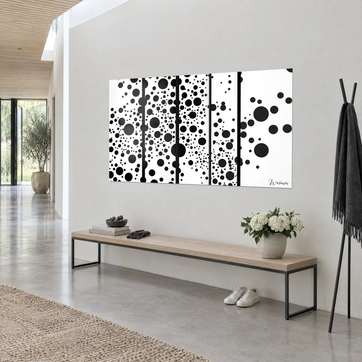 Tableau constellation de ronds ébène en cinq volets blancs, accroché de trois-quarts au-dessus d'un banc bois et fleurs blanches
