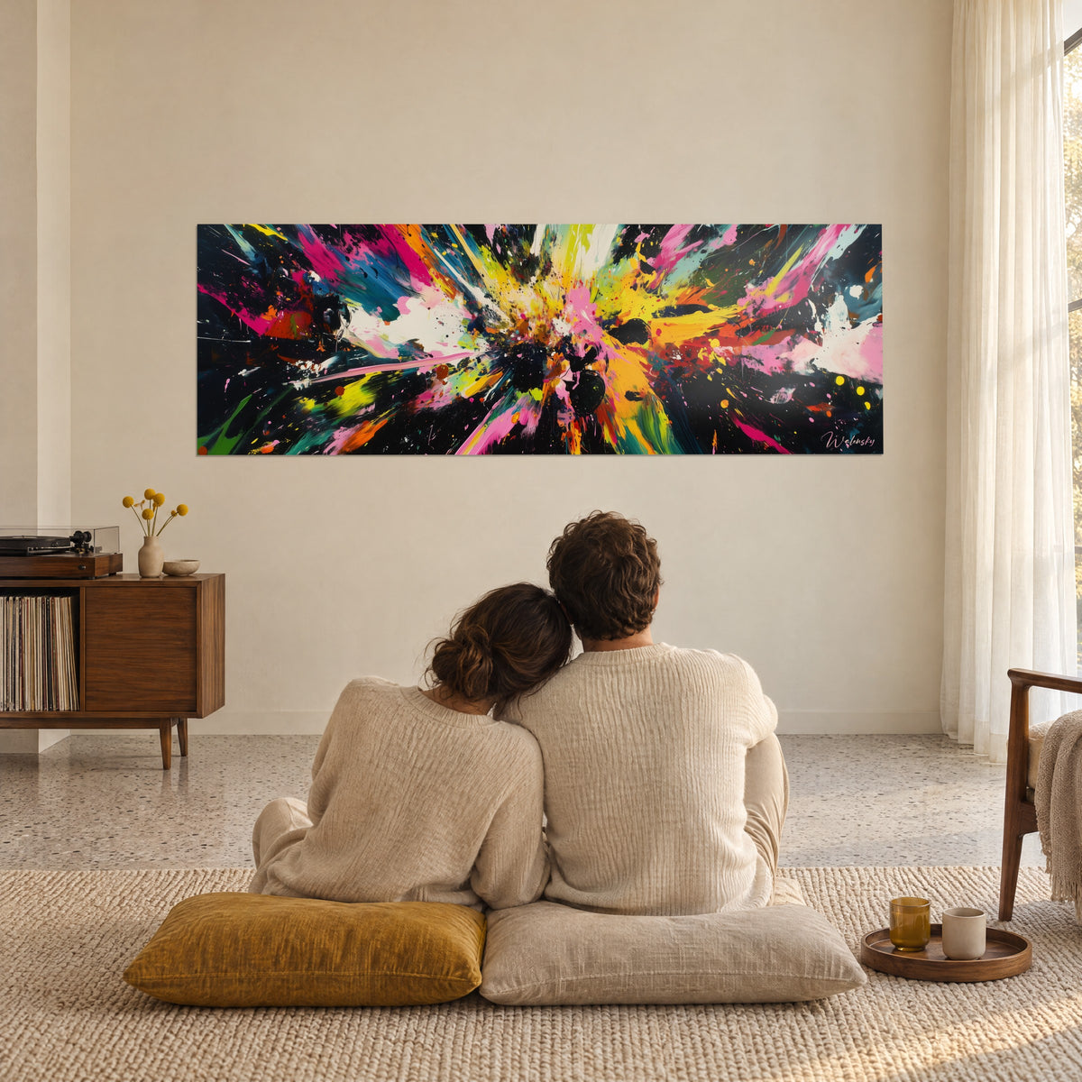 Cuadro fuegos artificiales abstractos con chorros turquesa, rosas y amarillos sobre fondo negro, frente a una pareja sentada en el suelo