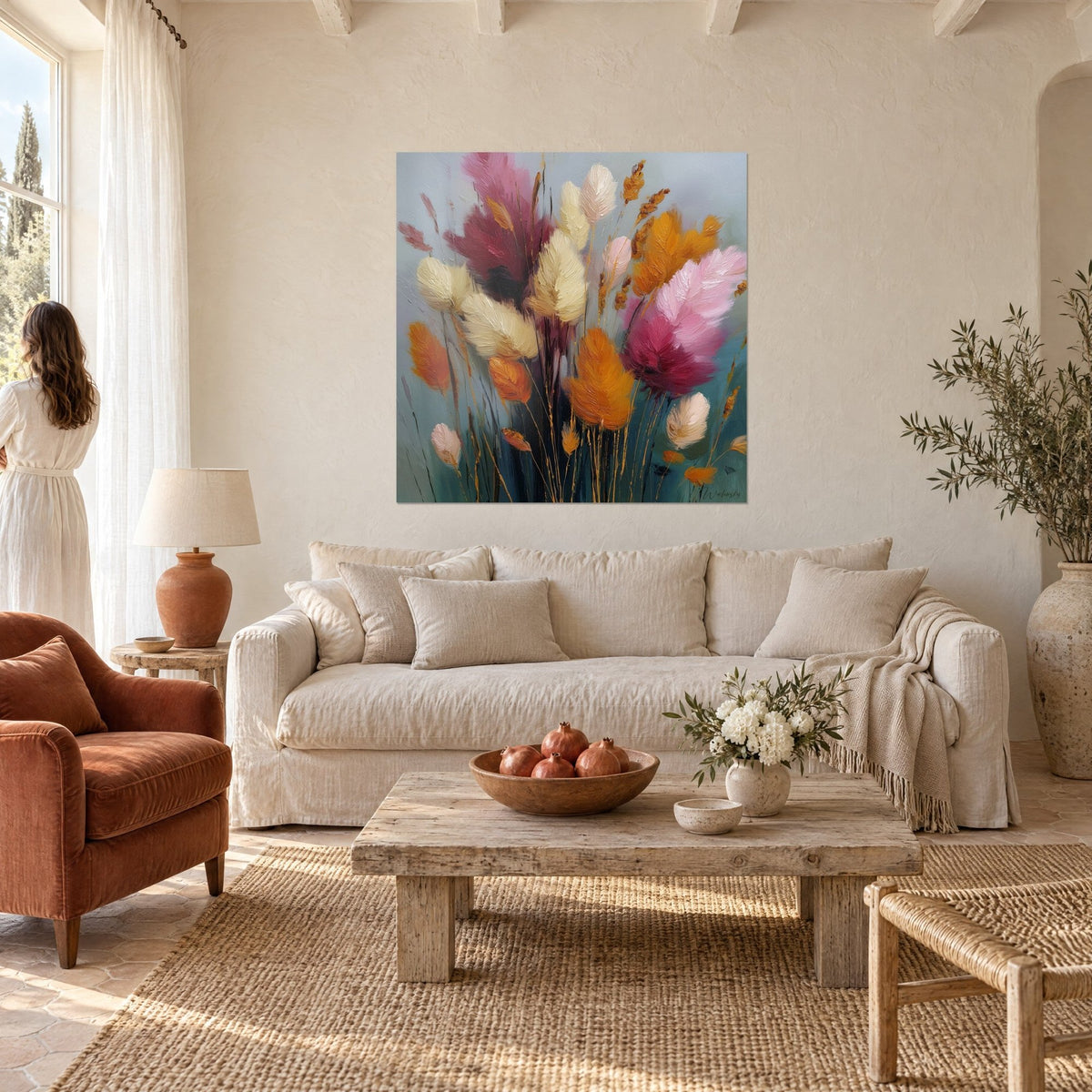 Tableau bouquet de graminées en plumes rose fuchsia et orangé, fond bleu-gris, au-dessus d'un canapé dans un salon lumineux