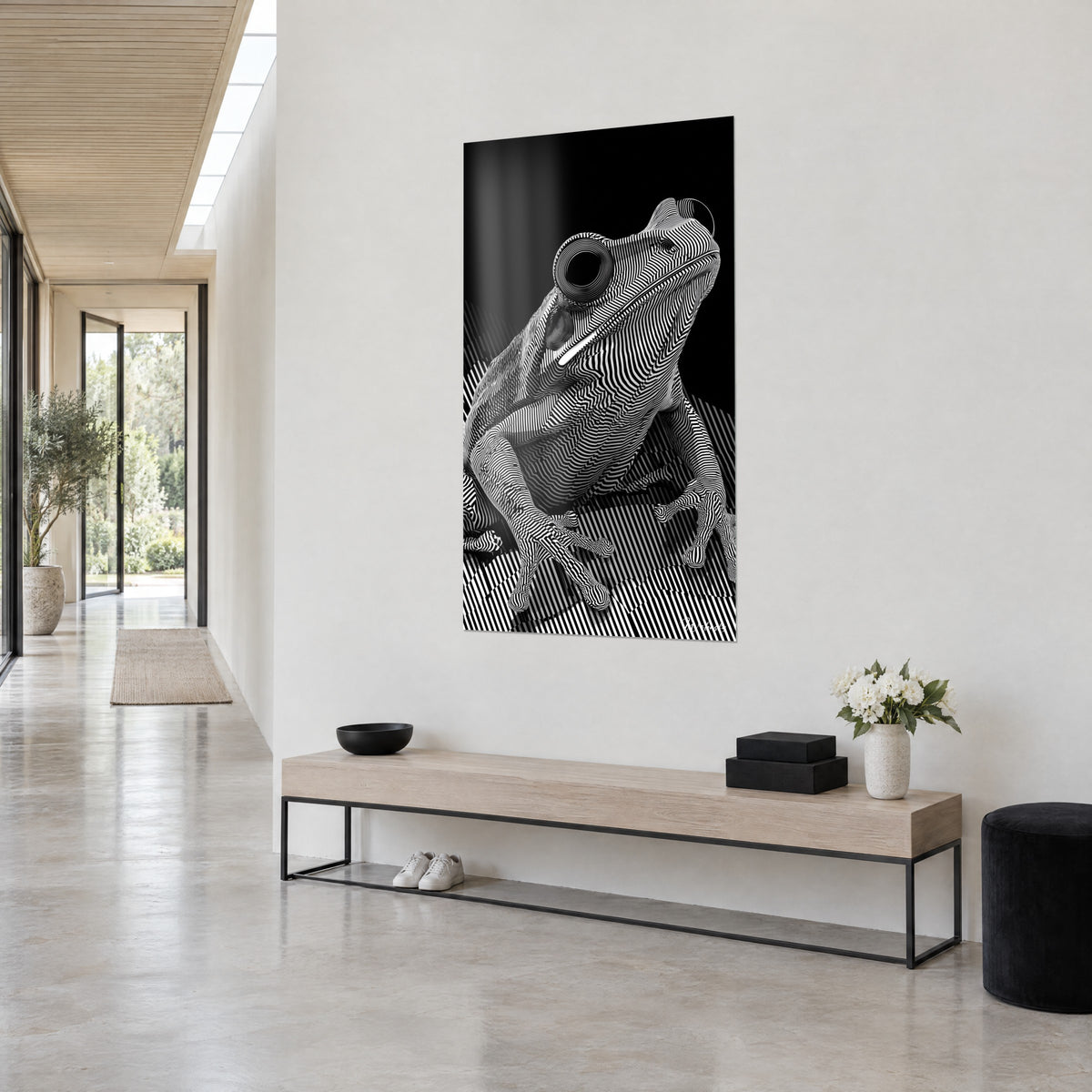 Quadro Anfibio con ondulazioni bianche su sfondo nero, occhio concentrico, appeso in un corridoio chiaro accanto a una panca di legno