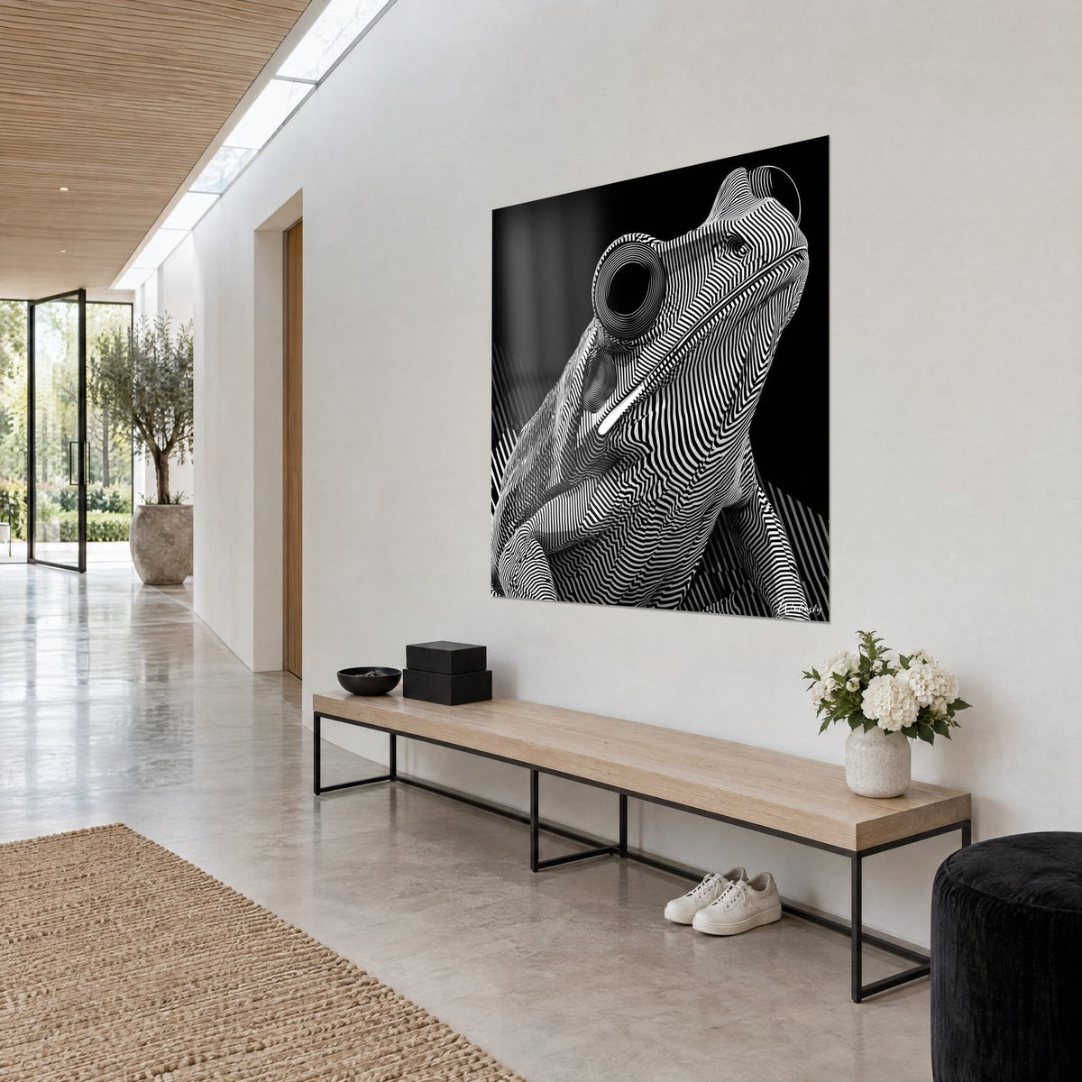 Gemälde Froschartiges Tier mit weißen Arabesken auf Schwarz, angehobene Schnauze und umkreistes Auge, an der Wand eines hellen Flurs, Holzbank und beiger Boden