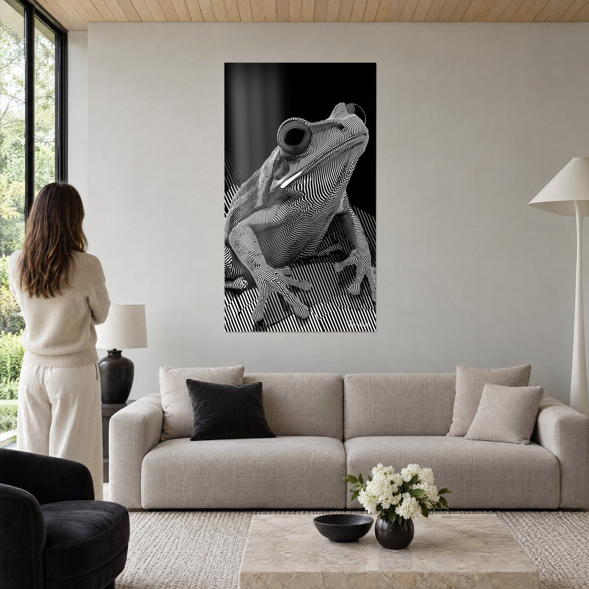 Quadro Rana zebrata in bianco e nero con occhio a spirale, osservata da una donna di spalle, sopra un divano in un soggiorno luminoso