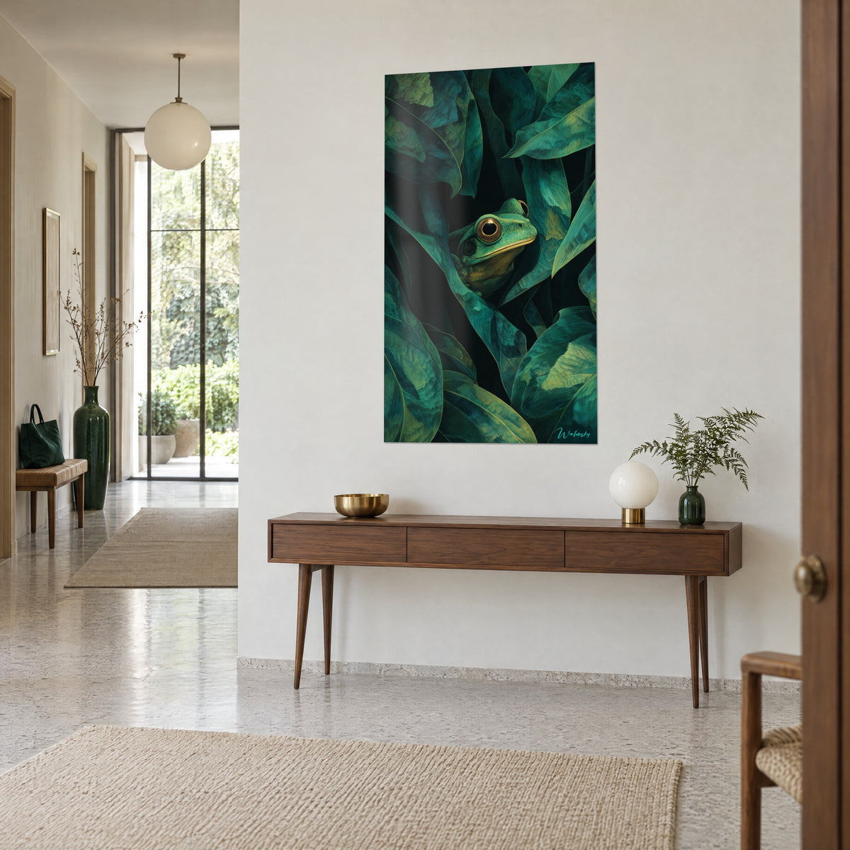 Quadro raganella smeraldo annidata tra grandi foglie verde-azzurre e nere, occhio bordato di rame, consolle in legno, ingresso luminoso