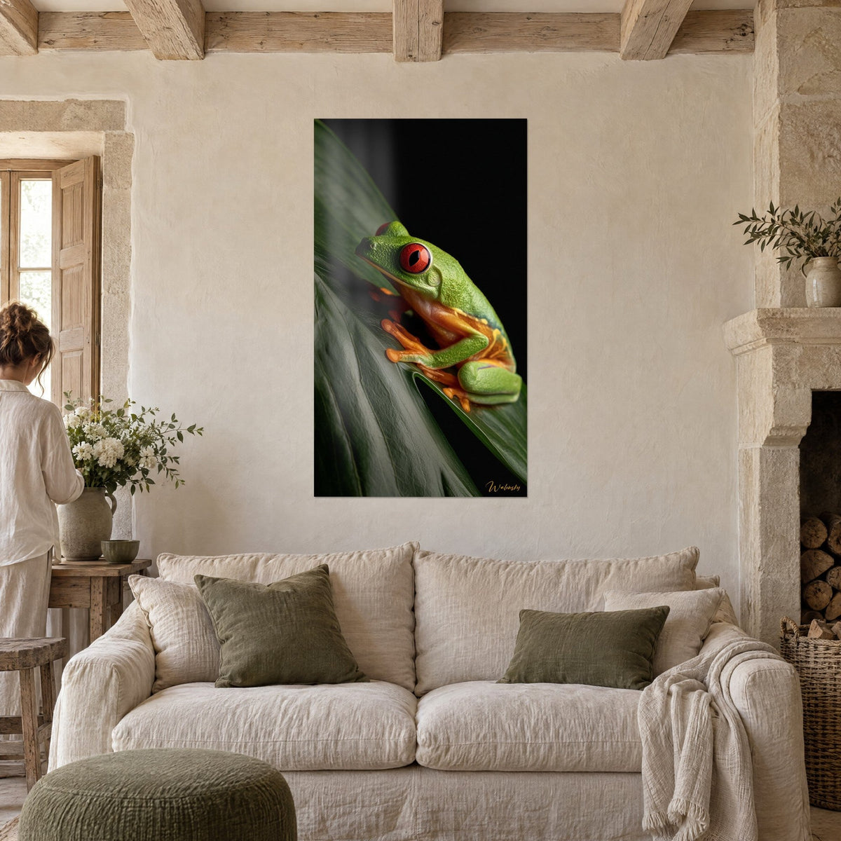 Wall art green tree frog with red eyes perched on a dark leaf, black background, hung in a stone living room above the sofa in a bright lounge