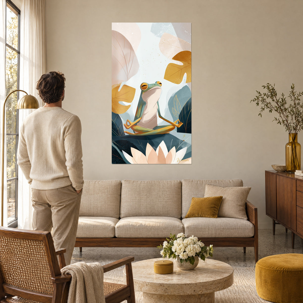 Wall art frog in lotus pose with hands joined, ochre and petrol blue leaves, a man seen from behind above a sofa in a bright living room
