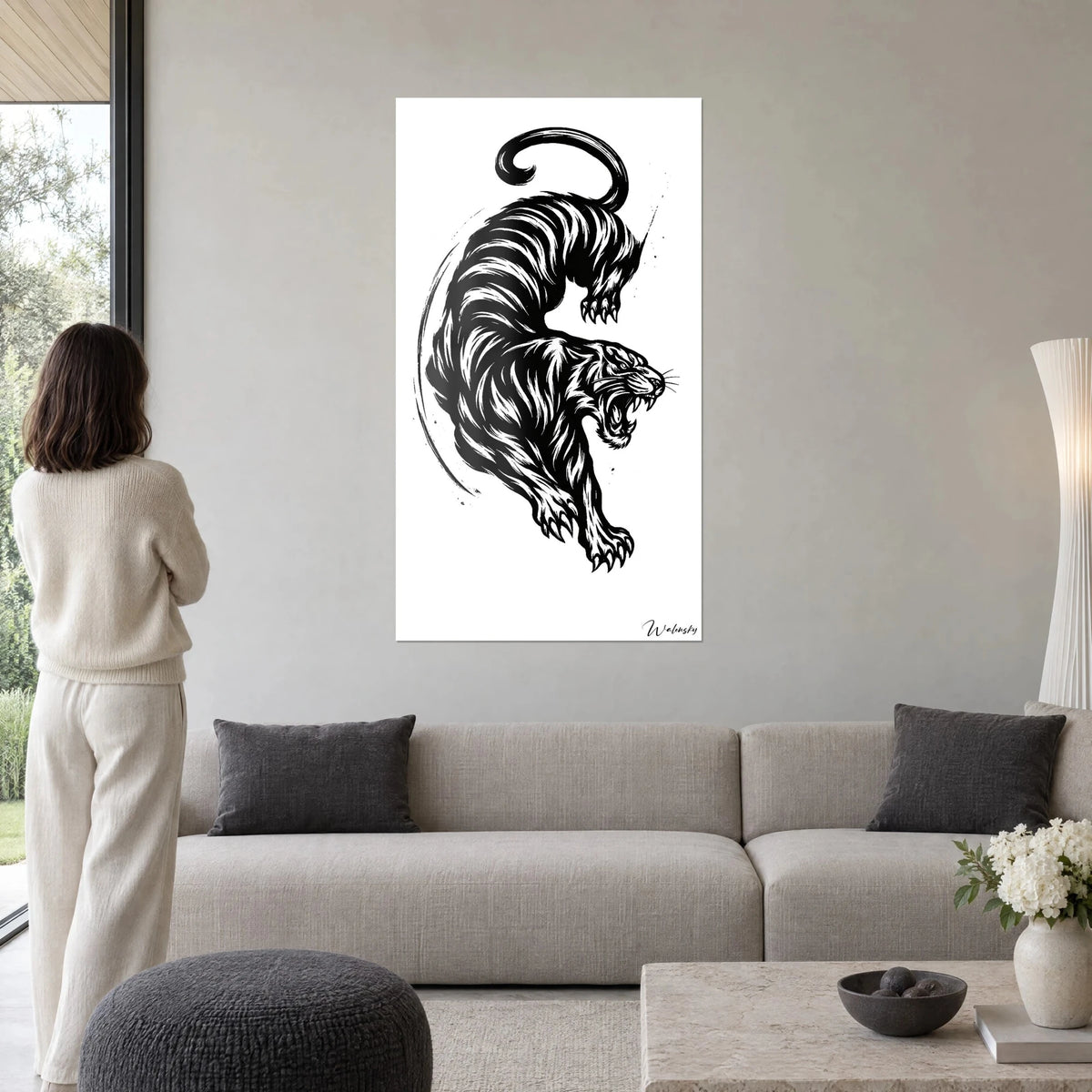 Quadro di una tigre che striscia in inchiostro nero su fondo bianco, fauci ruggenti, sopra un divano in un soggiorno luminoso