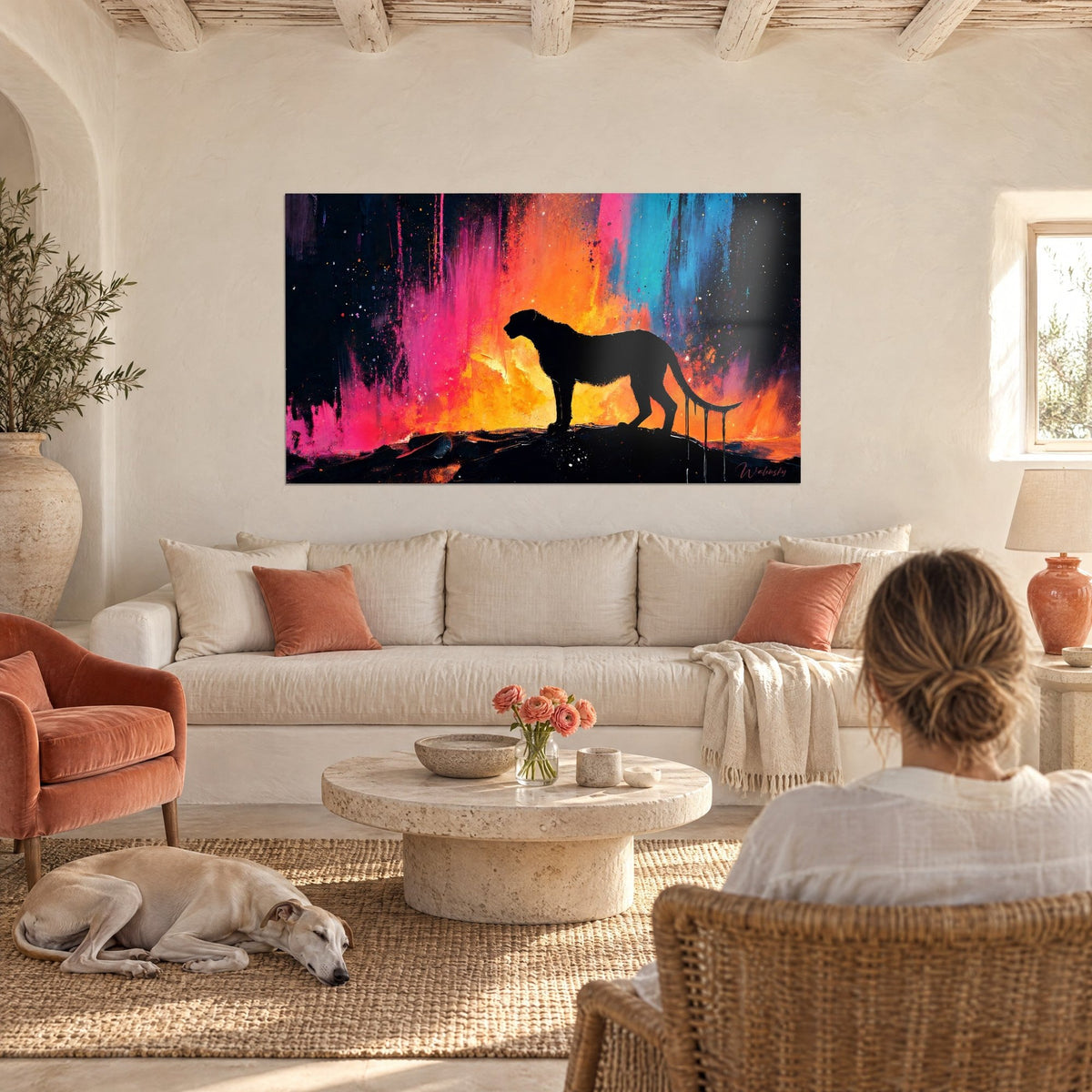 Schilderij cheetah als zwarte silhouet voor felroze en oranje verfdruipers, boven een bank in een lichte woonkamer