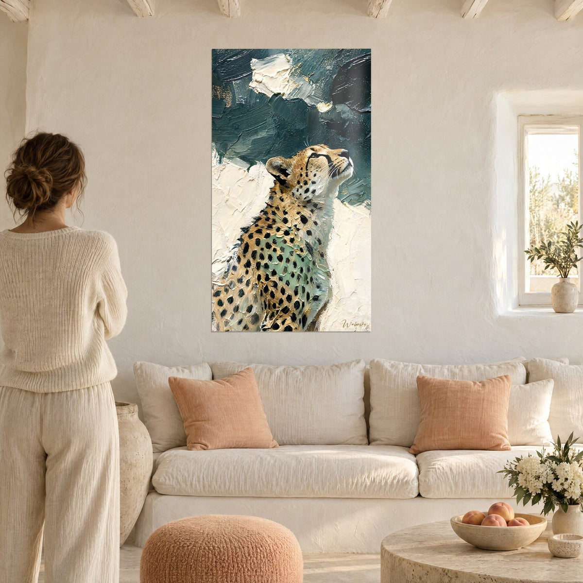 Wall art cheetah with ochre fur speckled in black, muzzle raised toward a thick blue-green background, above a sofa in a bright living room