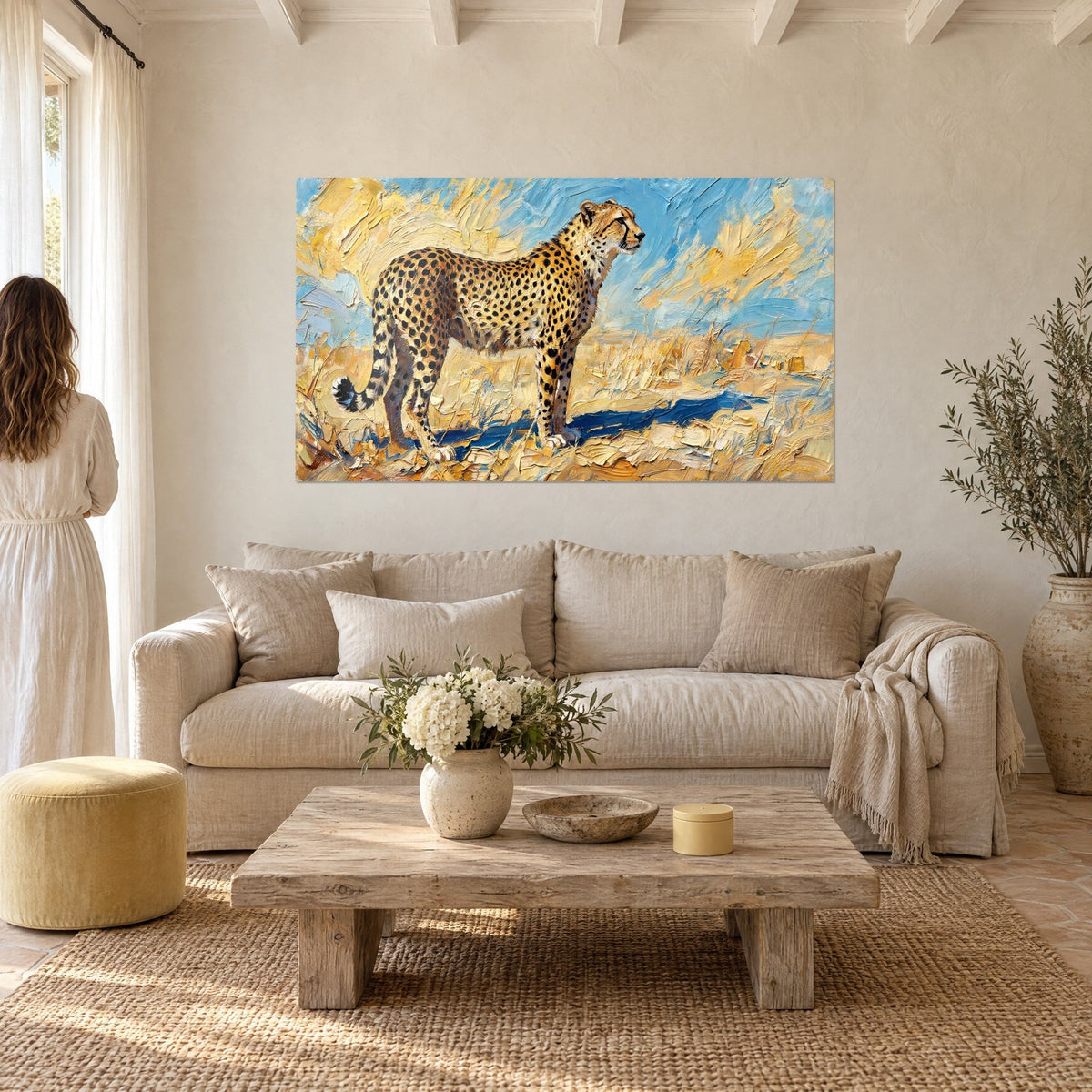 Tableau guépard tacheté au pelage doré sur fond bleu ciel, deux femmes de dos, au-dessus d'un canapé dans un salon lumineux