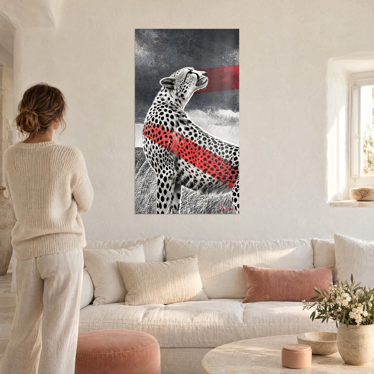 Gemälde Gepard mit gefleckter Schnauze nach oben gerichtet, leuchtend rotes Band auf stahlgrauem Hintergrund, Frau von hinten, über einem Sofa in einem hellen Wohnzimmer