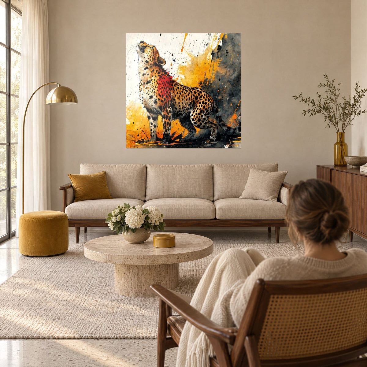 Wall art cheetah with muzzle raised, black spots and red splash on ochre background, above a sofa in a bright living room