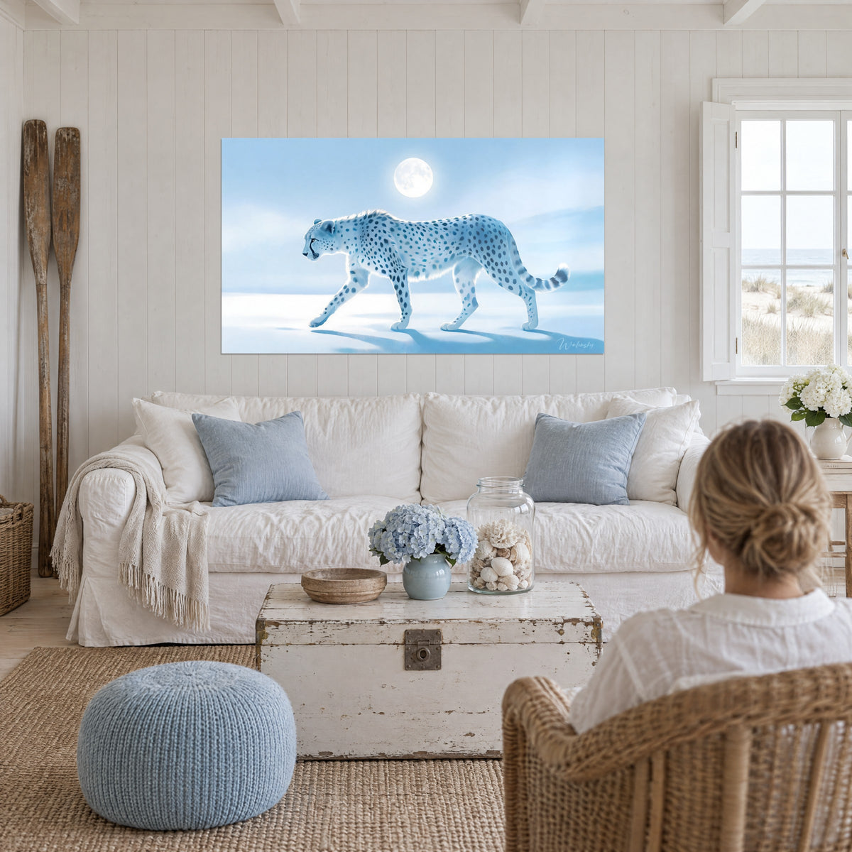 Wall art white cheetah dappled with blue under a full moon, pale snow, above a sofa in a bright living room