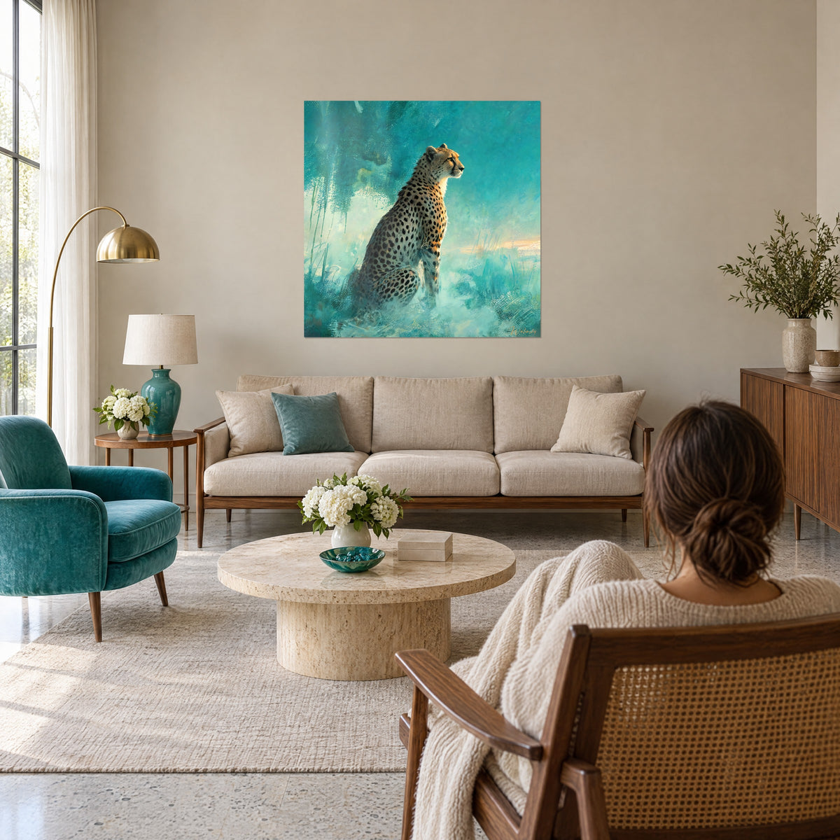 Tableau félin tacheté assis, profil tourné vers l'horizon, fond turquoise et sable, femme de dos, au-dessus d'un canapé dans un salon lumineux