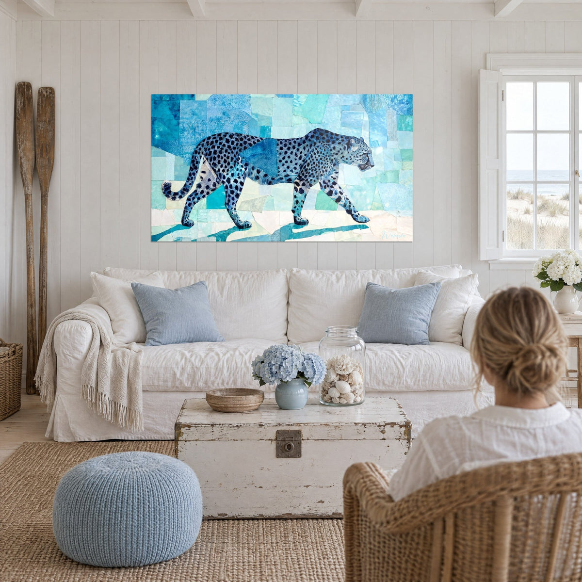 Quadro di un ghepardo in cammino, manto blu punteggiato di nero su mosaico turchese e bianco, sopra un divano in un soggiorno luminoso
