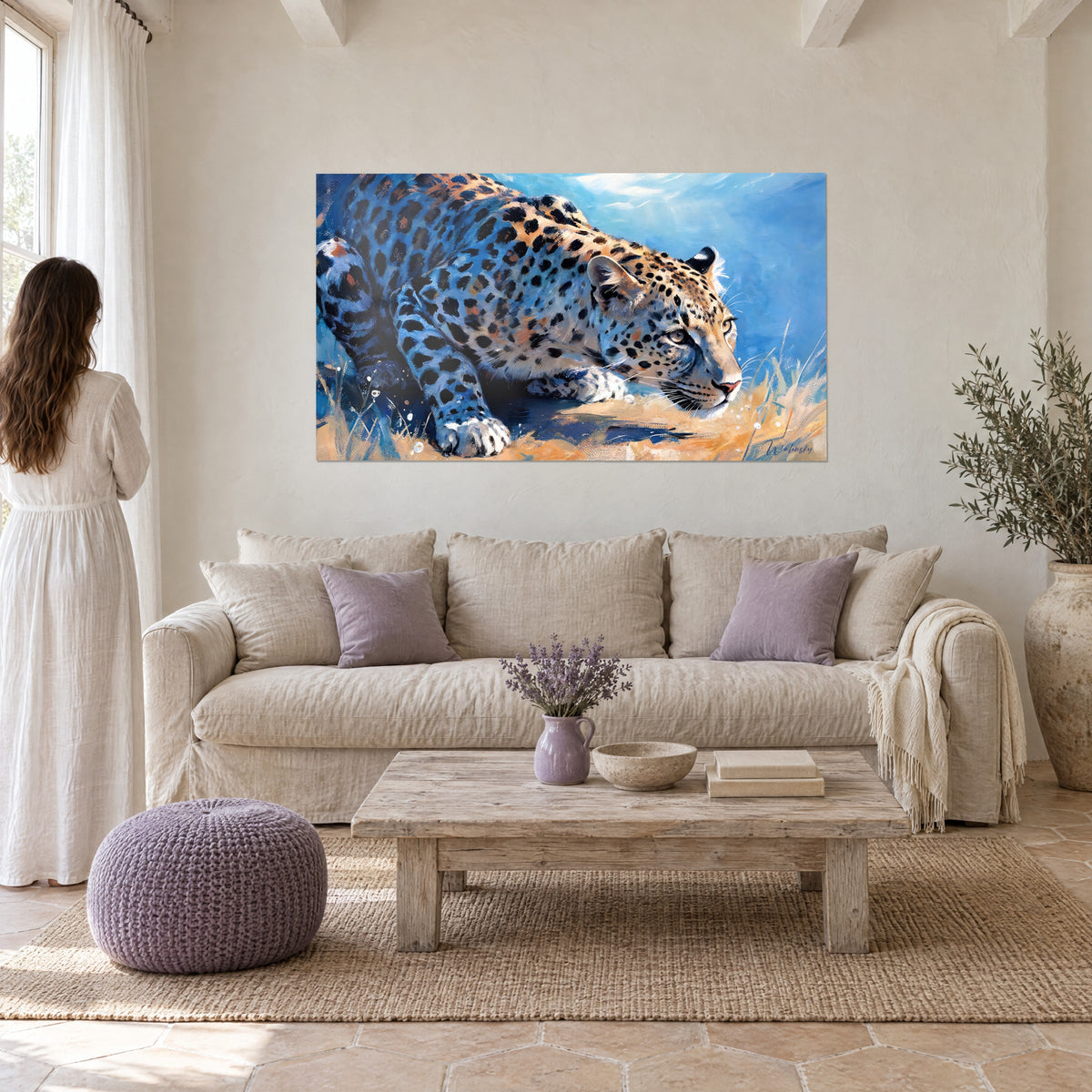 Quadro di un felino maculato accovacciato nell'erba ocra, manto blu cobalto e crema, sguardo fisso, sopra un divano in un soggiorno luminoso