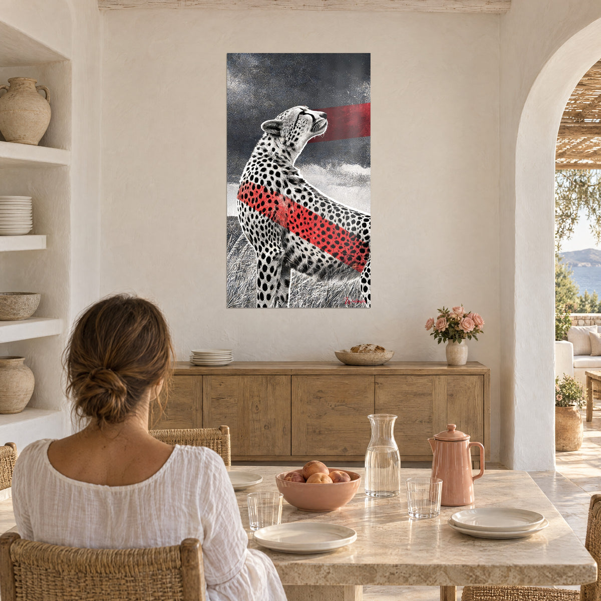 Wall art savannah leopard with black rosettes, red band across its back, grey grass, woman seen from behind at a table, Mediterranean house