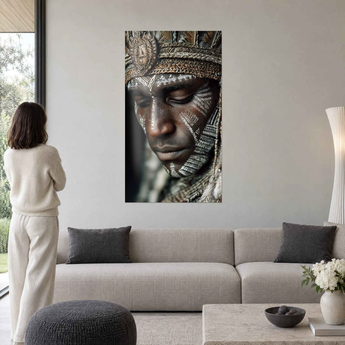 Wall art of a warrior with closed eyelids, white face paint and brown braided headdress, above a sofa in a bright living room