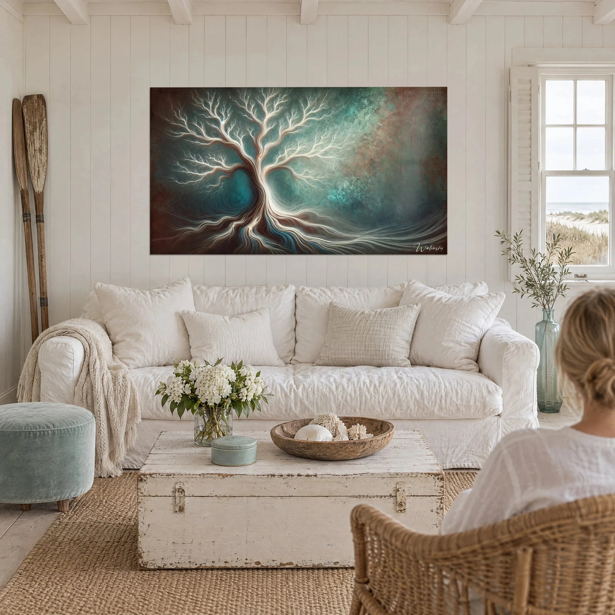 Schilderij witte boom met fijne takken op turquoise en roestkleurige achtergrond, twee vrouwen van achteren, boven een bank in een lichte woonkamer