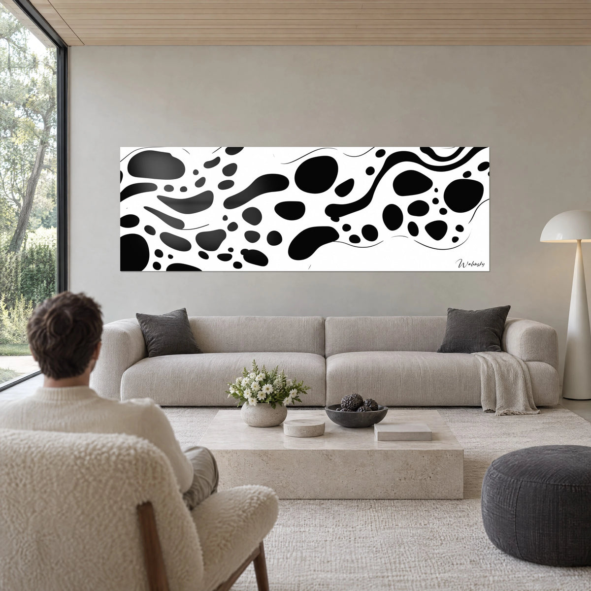 Quadro panoramico di macchie nere organiche su fondo bianco, sottili linee ondulate, sopra un divano in un soggiorno luminoso