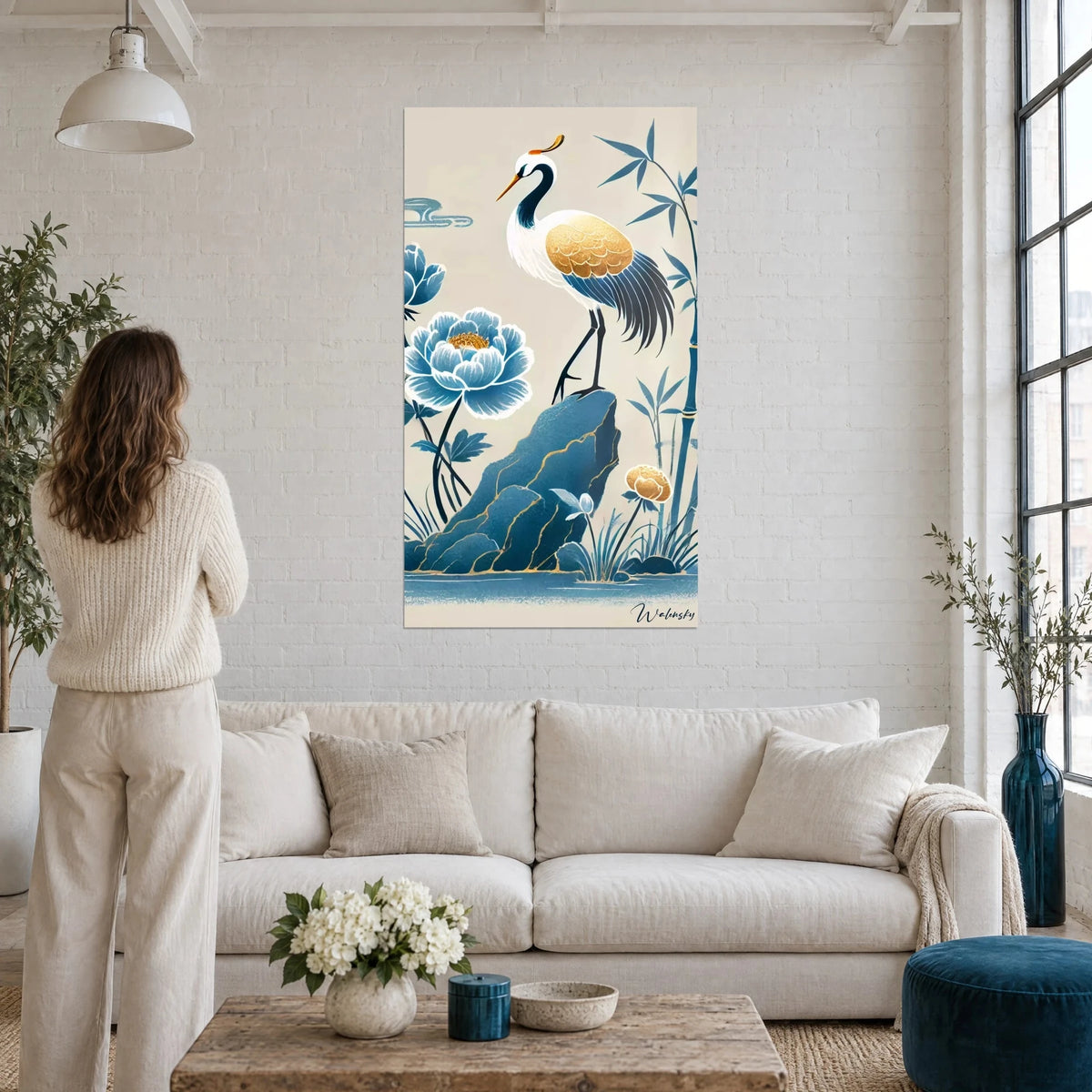 Tableau grue au plumage doré perchée sur un rocher bleu, pivoine et bambou sur fond crème, au-dessus d'un canapé dans un salon lumineux