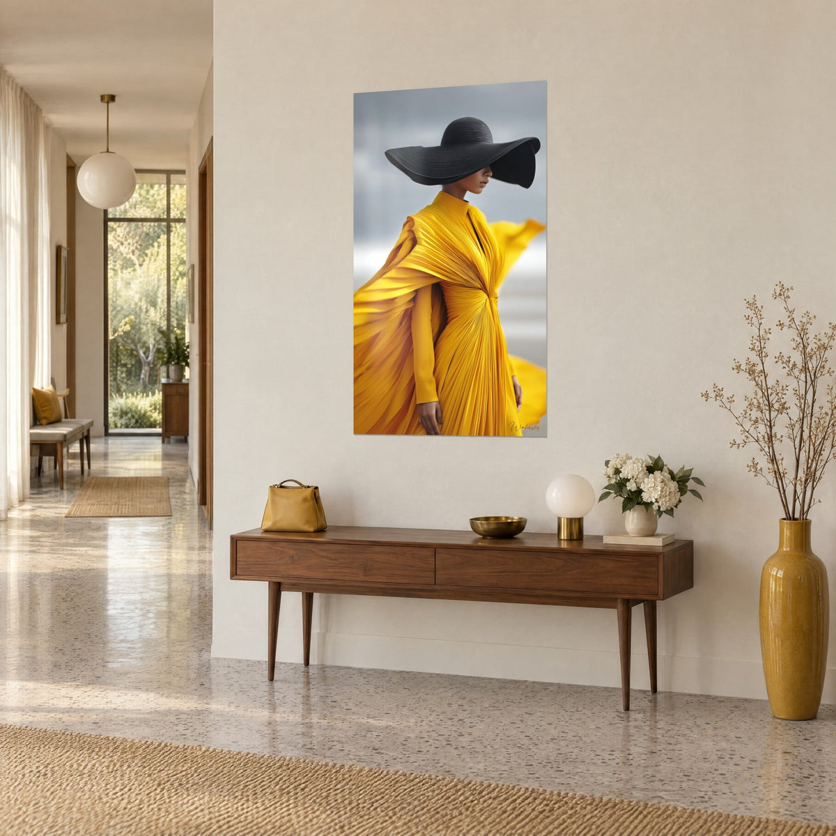 Quadro figura slanciata in abito plissettato giallo senape e mantella nera su sfondo grigio nuvoloso, sopra una consolle in legno in un corridoio chiaro