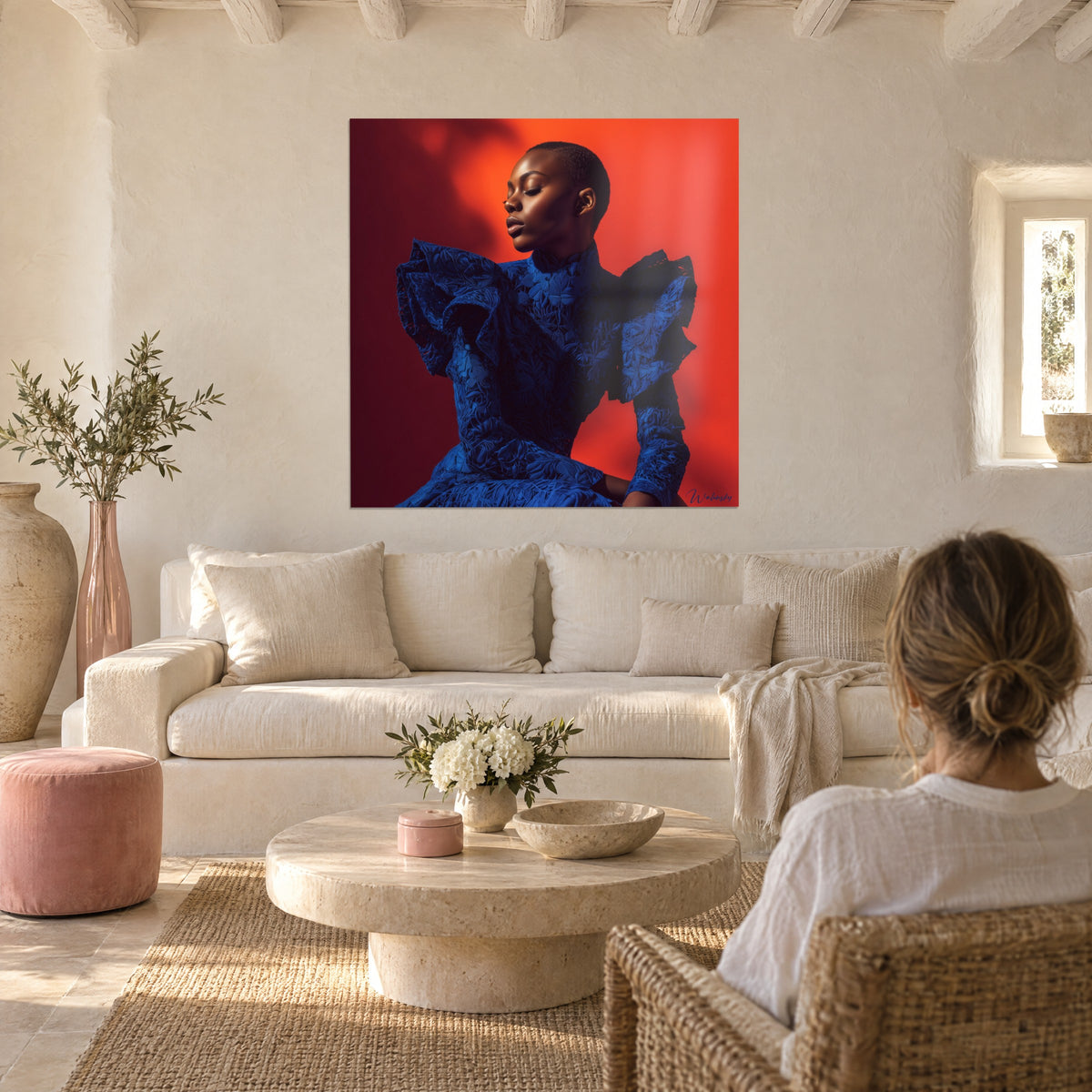Gemälde einer Frau mit kahlrasiertem Kopf in einem Spitzenkleid königsblau, leuchtend oranger Hintergrund, über einem Sofa in einem hellen Wohnzimmer