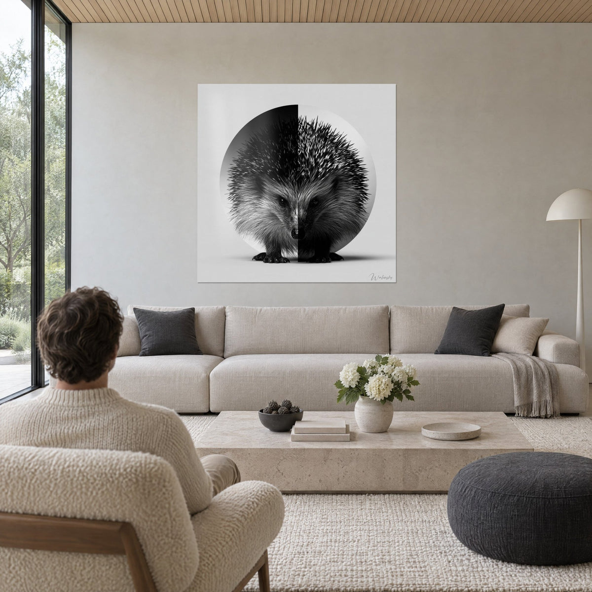 Tableau hérisson de face, piquants noirs et gris perle sur disque scindé, homme de dos, au-dessus d'un canapé dans un salon lumineux