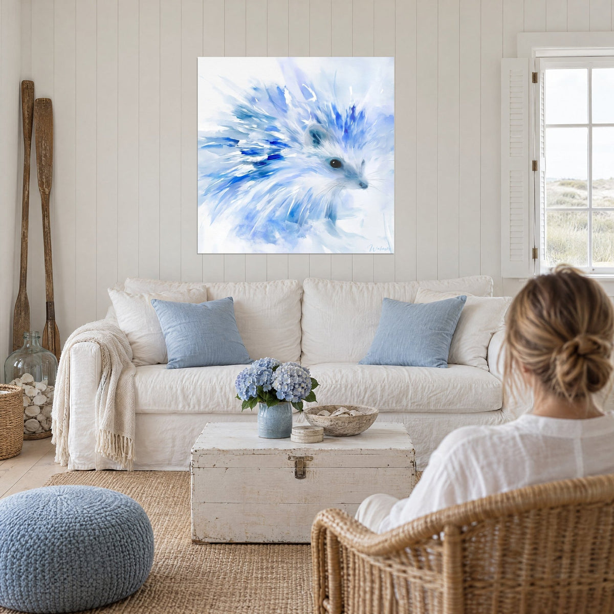 Schilderij egel met uiteenspattende ultramarijnblauwe stekels op een ijzig witte achtergrond, boven een bank in een lichte woonkamer