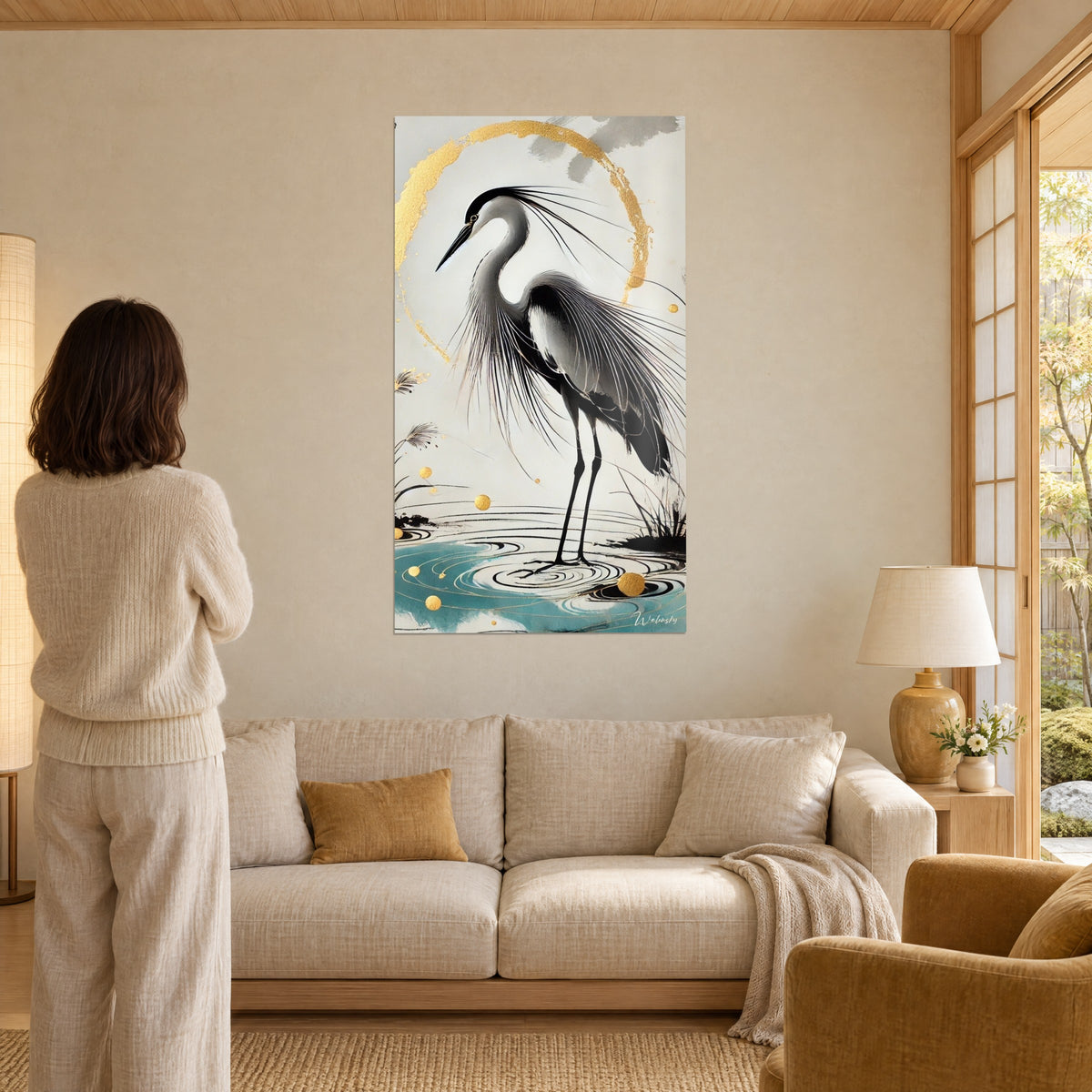 Gemälde Graureiher mit langen grauen Federn, goldener Kreis und türkisfarbenes Wasser, vor einer Frau von hinten, über einem Sofa in einem hellen Wohnzimmer