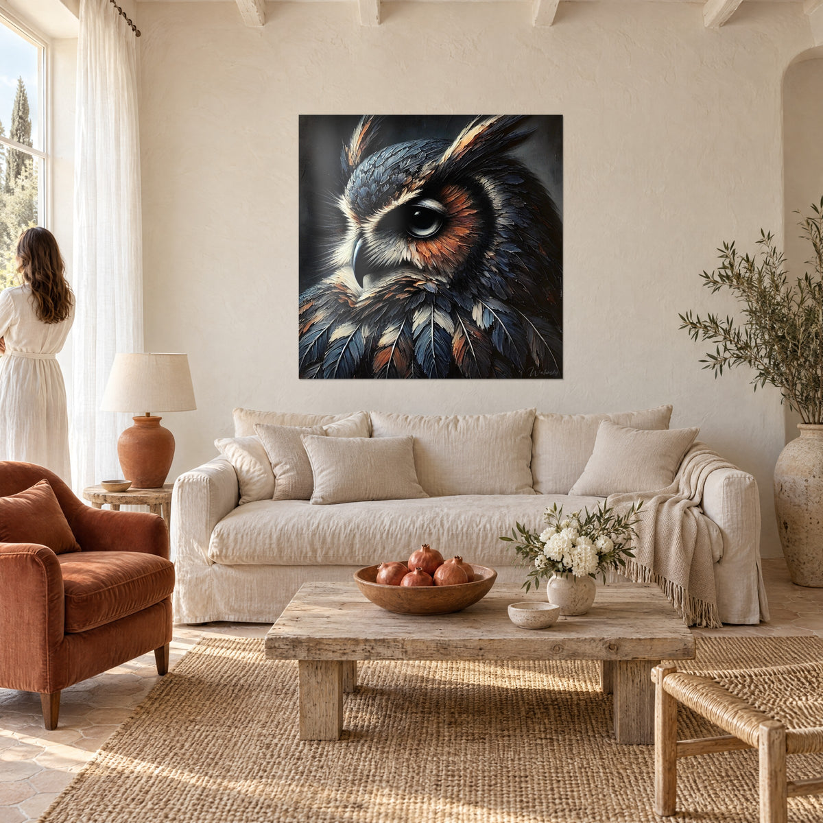 Tableau hibou grand-duc aux plumes bleu nuit et fauve cuivré, regard noir, femme de dos au-dessus d'un canapé dans un salon lumineux
